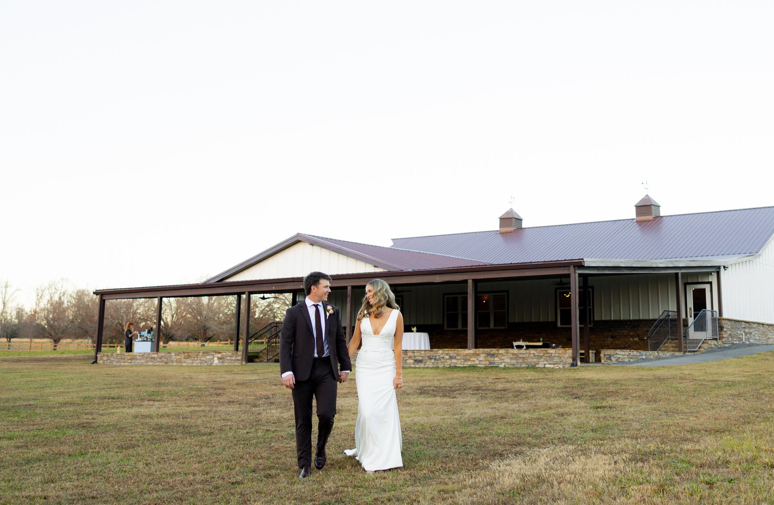 A bride and groom walking hand in hand outdoors at a wedding reception venue with a classic reception space for NC weddings and events 