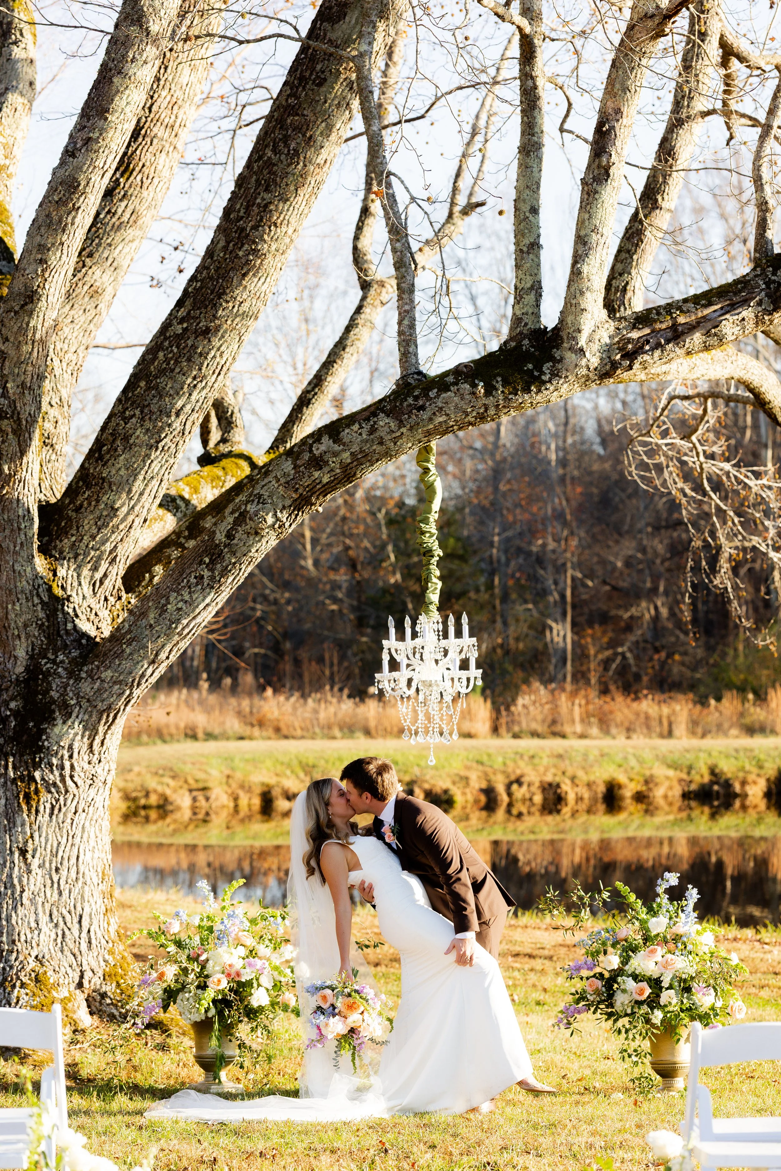 A bride and groom sharing a kiss outdoors during a wedding ceremony at Sable and Vine's ceremony tree at the Granville County wedding and event venue Sable and Vine formerly The Barn at Vino