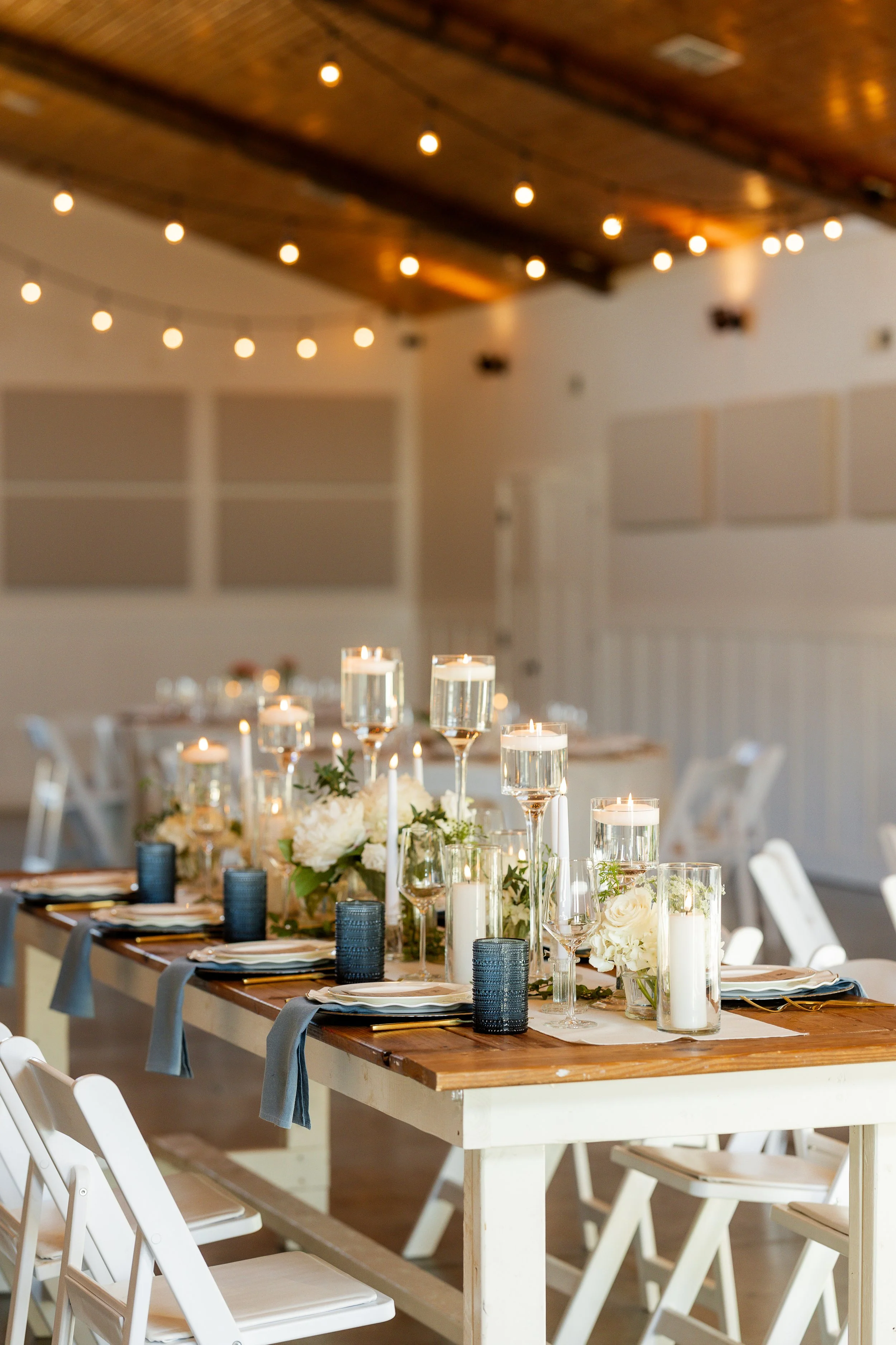 Wedding reception table with floral centerpiece, candles, glassware, and table settings in Sable and Vine, a NC wedding venue in Stem