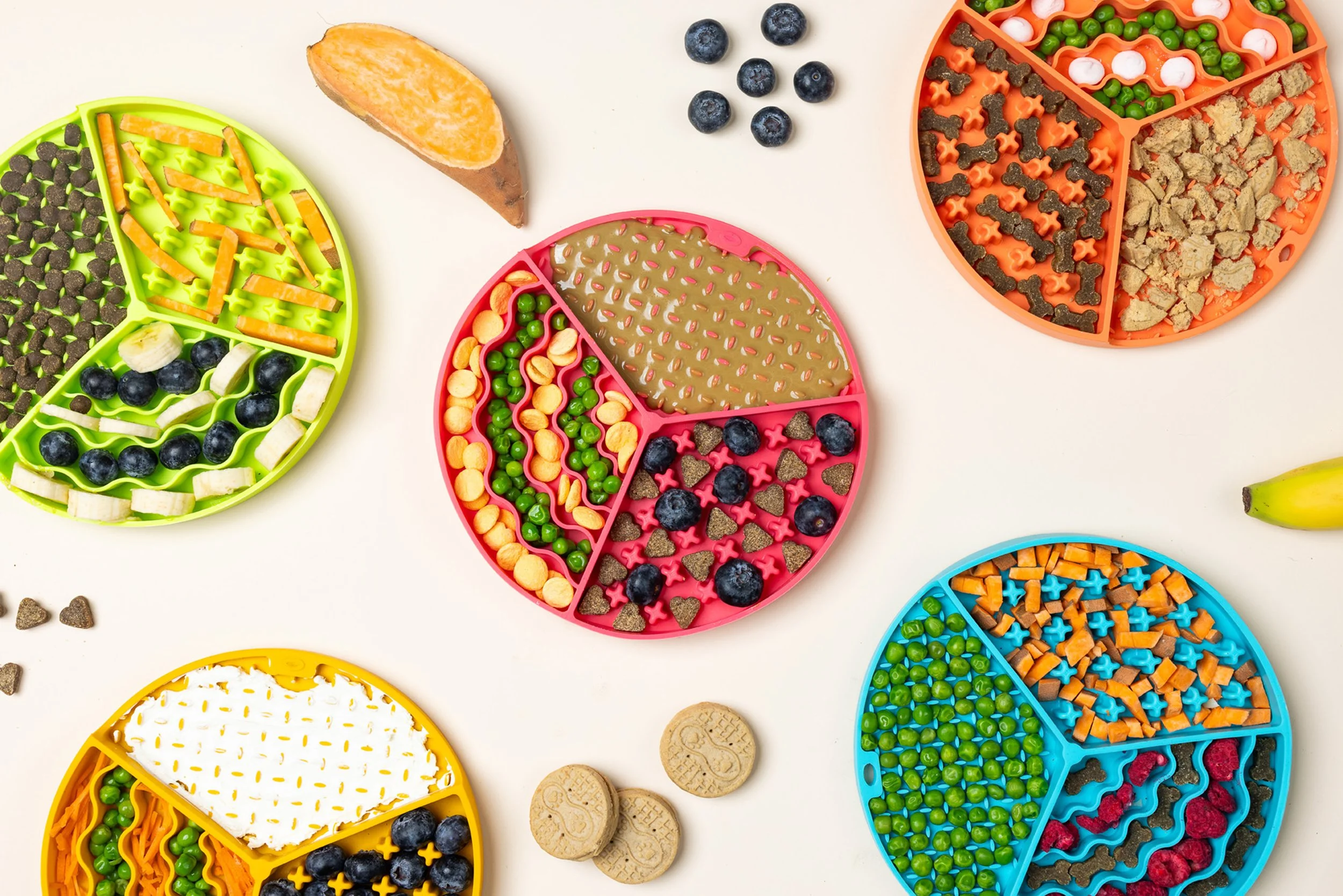 Colorful divided trays filled with various candies, blueberries, and some cookies on a white background.