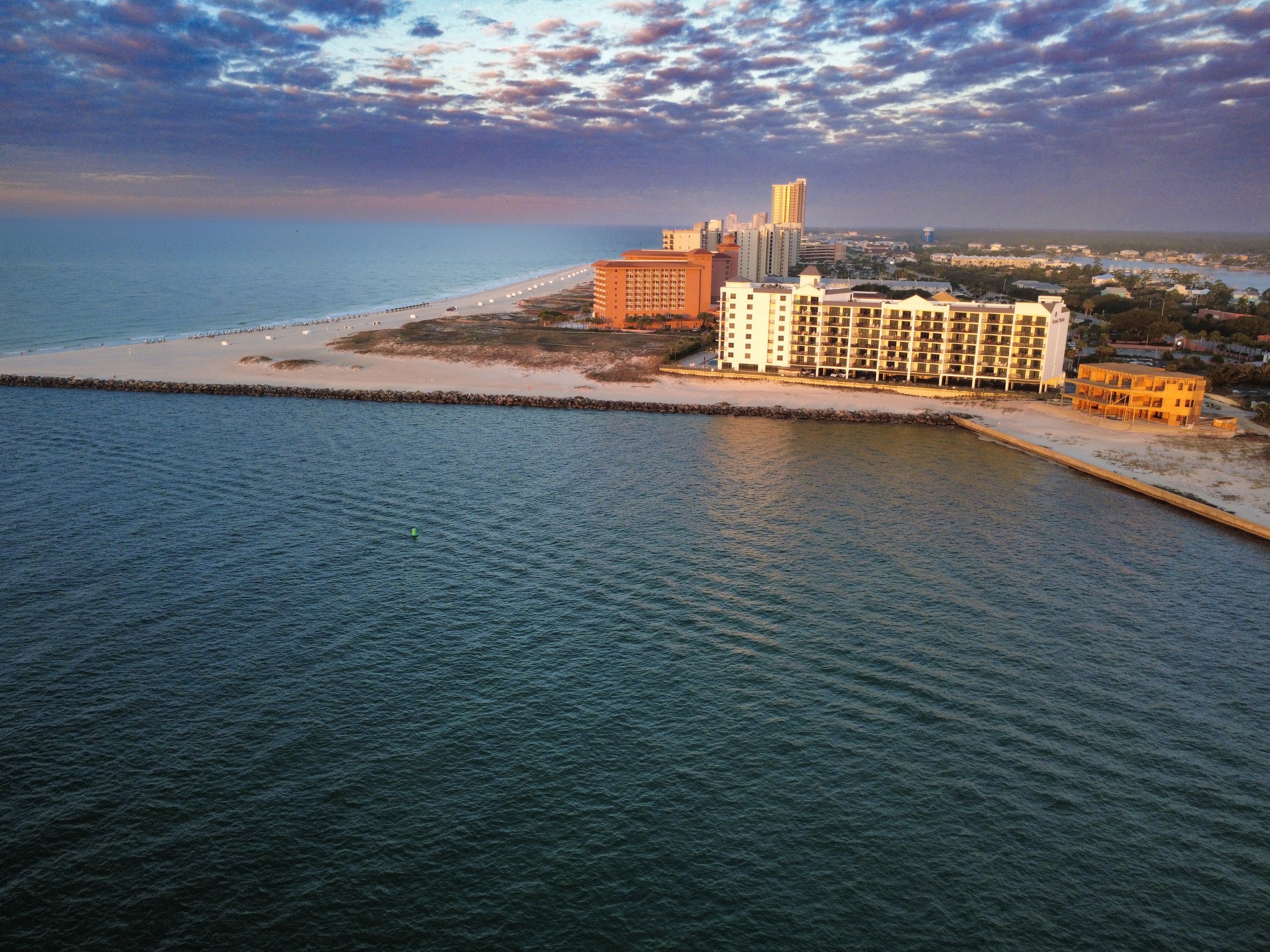 Aerial view of a coastal city with beachfront hotels and apartment buildings at sunset