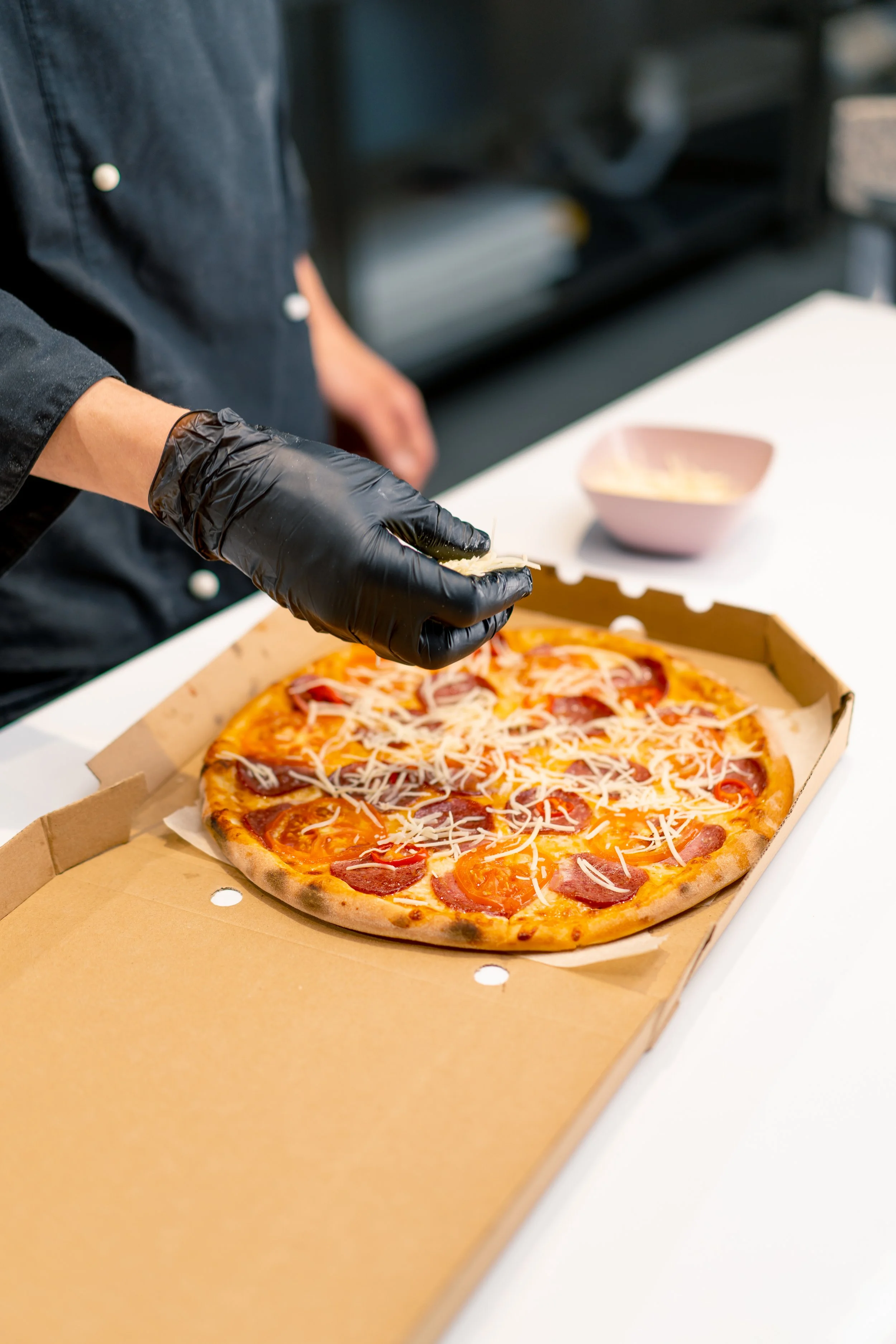 a-male-pizza-chef-sprinkles-mozzarella-cheese-on-a-2026-01-06-09-46-02-utc.jpg
