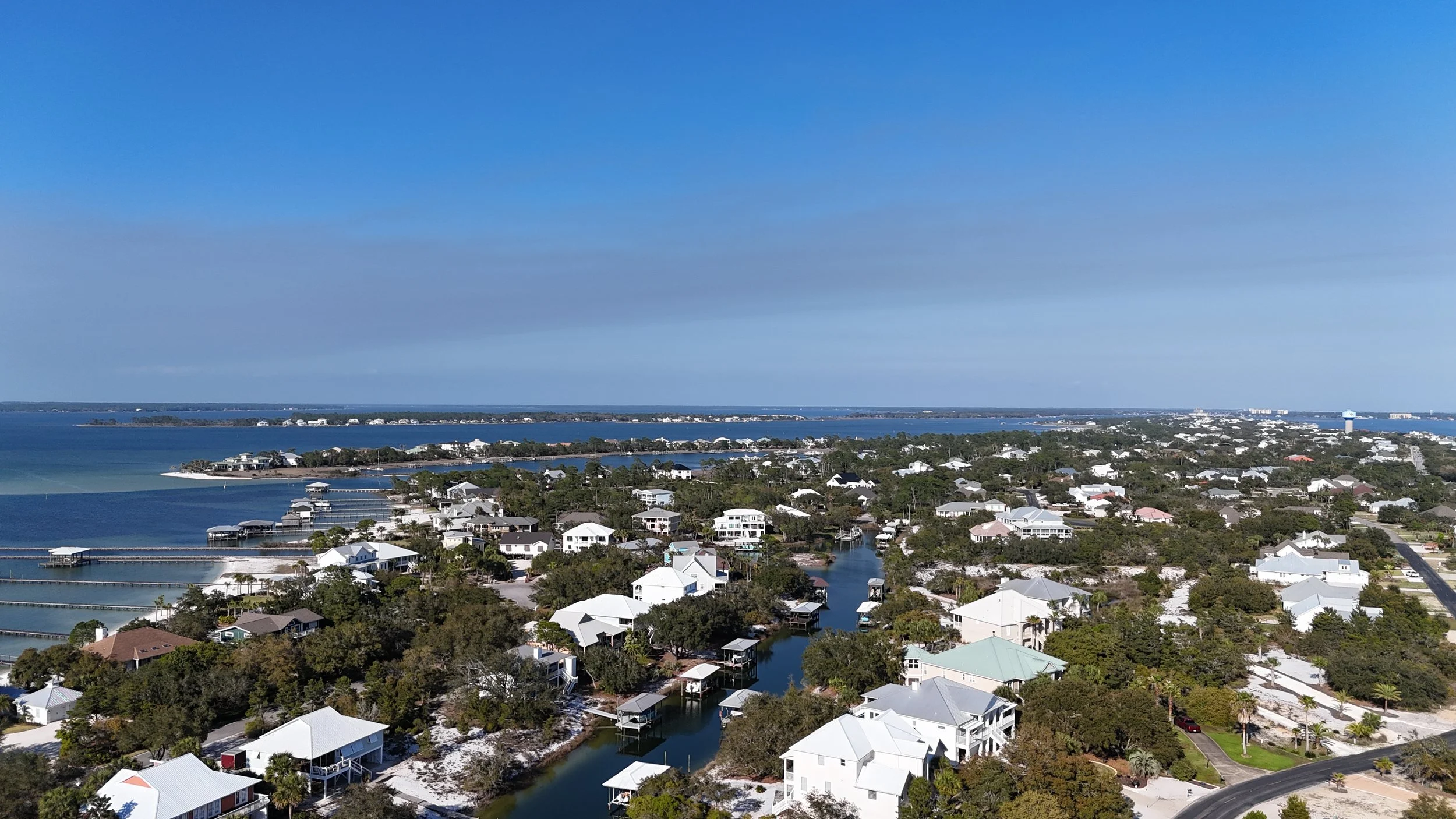 Drone aerial sunset view of Ono Island, Alabama coastline with homes and turquoise water.