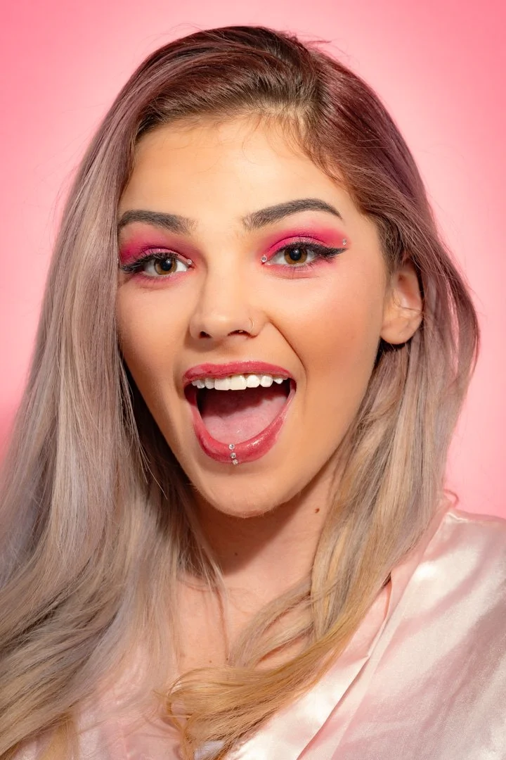 A pink themed picture - Mariah wearing a pink satin robe, pink Buttersky lipgloss, and hot pink eyeshadow in front of a pink backdrop