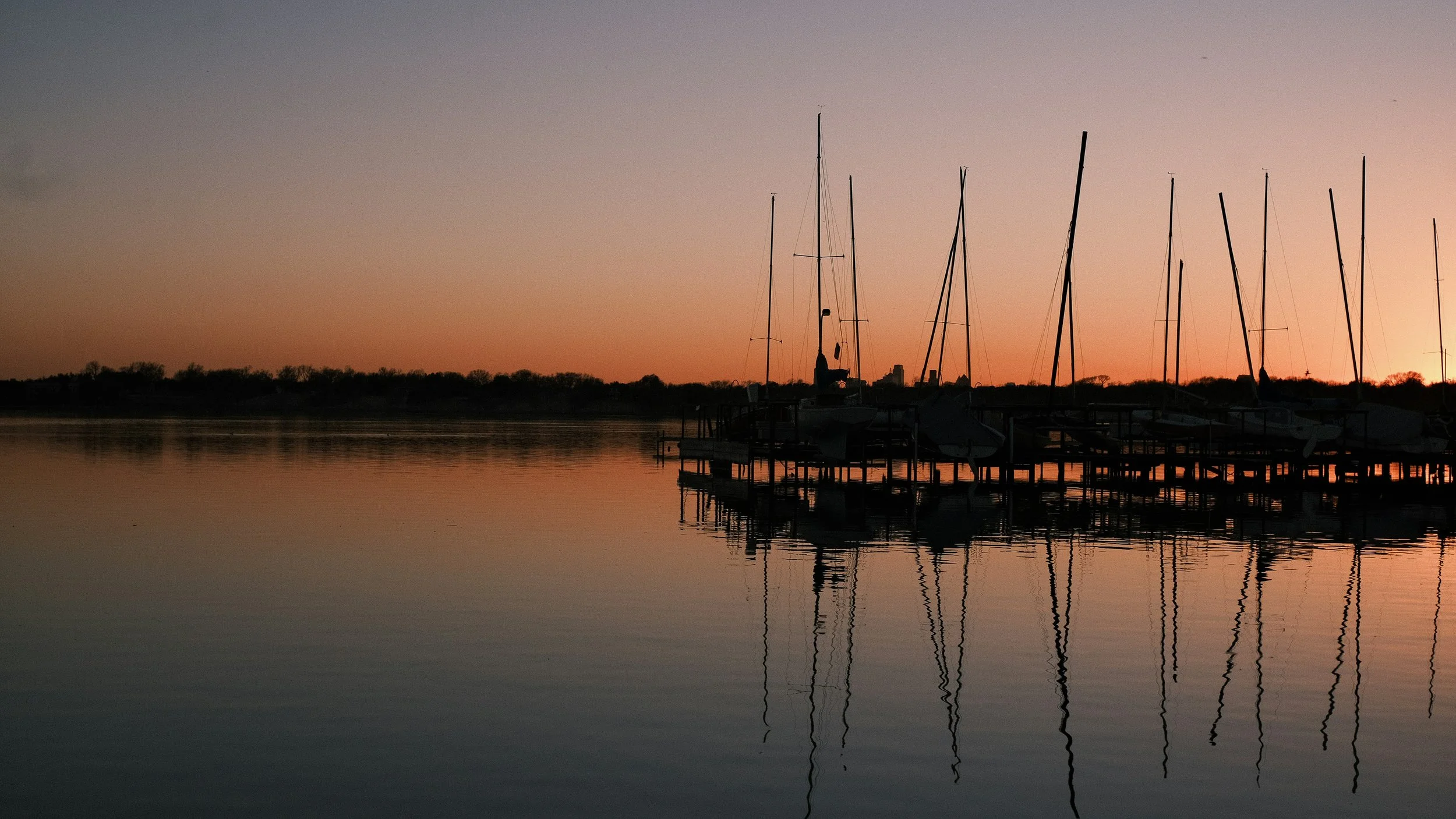A quiet harbor at dusk with a sailboats tethered