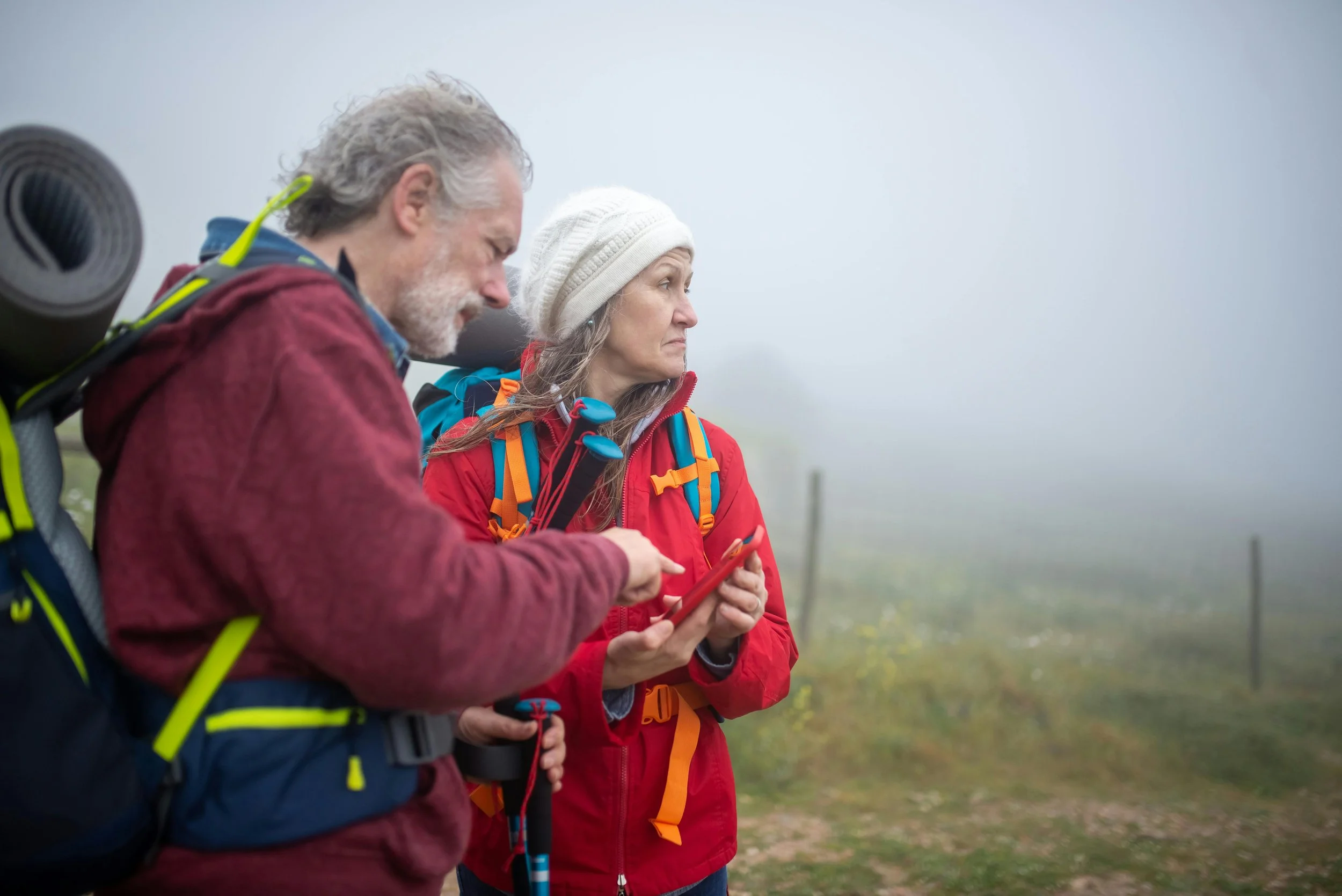 A couple hiking in the fog looking at their phone for directions