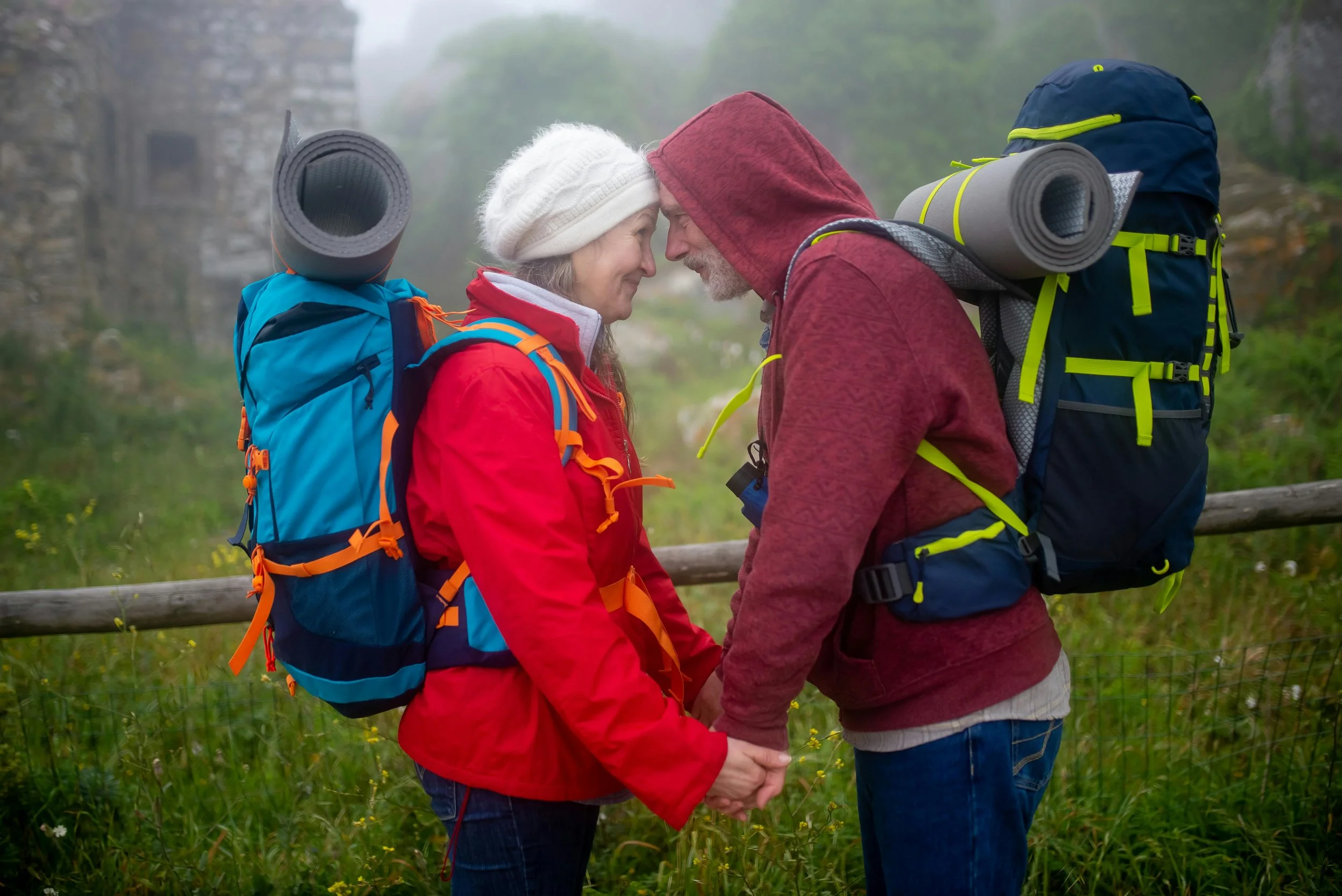 a couple with backpacks looking at each other smiling