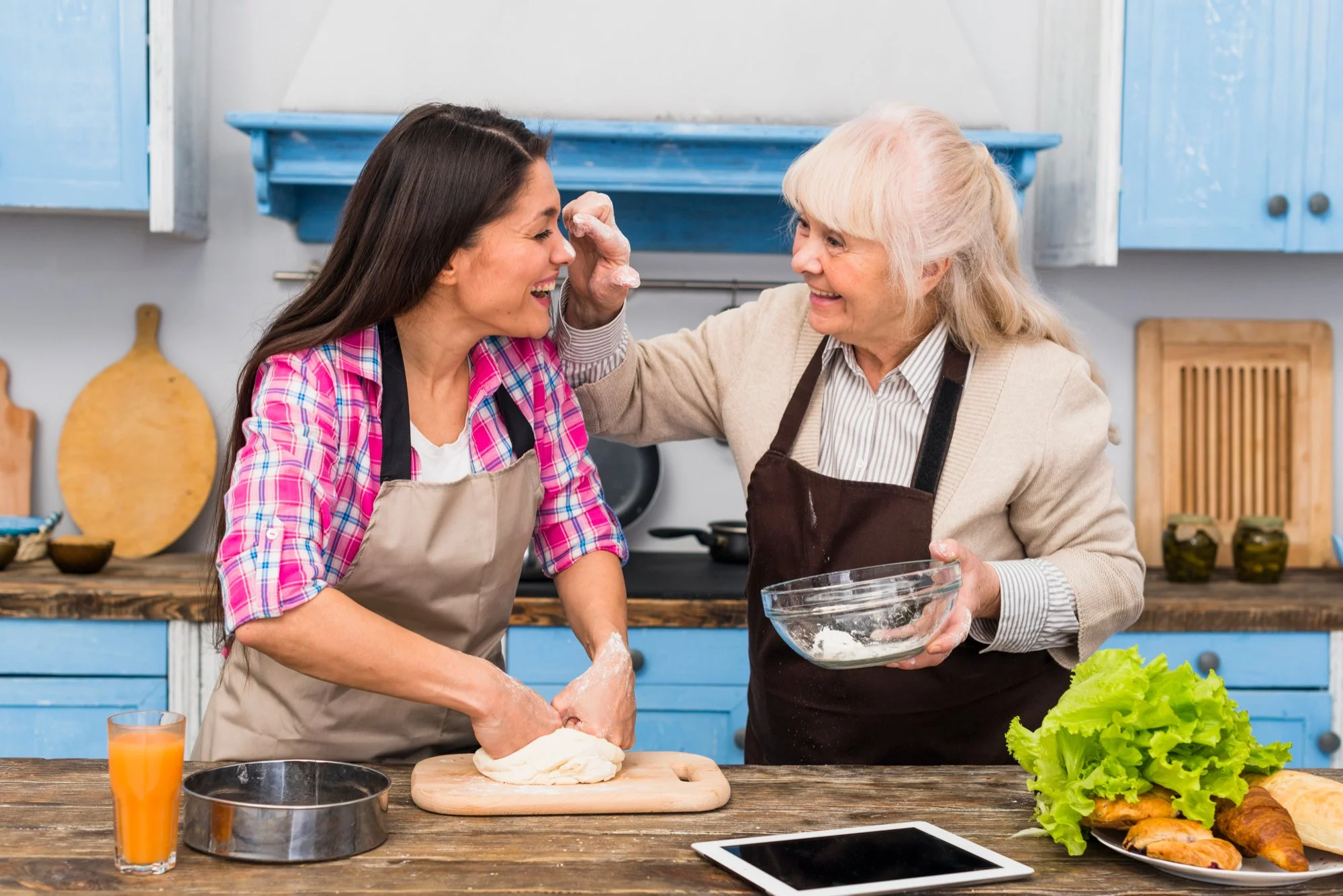 two women cooking and laughing together in the kitchen