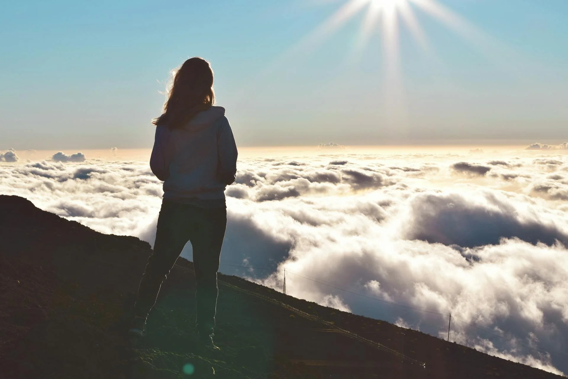 a woman on a mountain looking out over the clouds