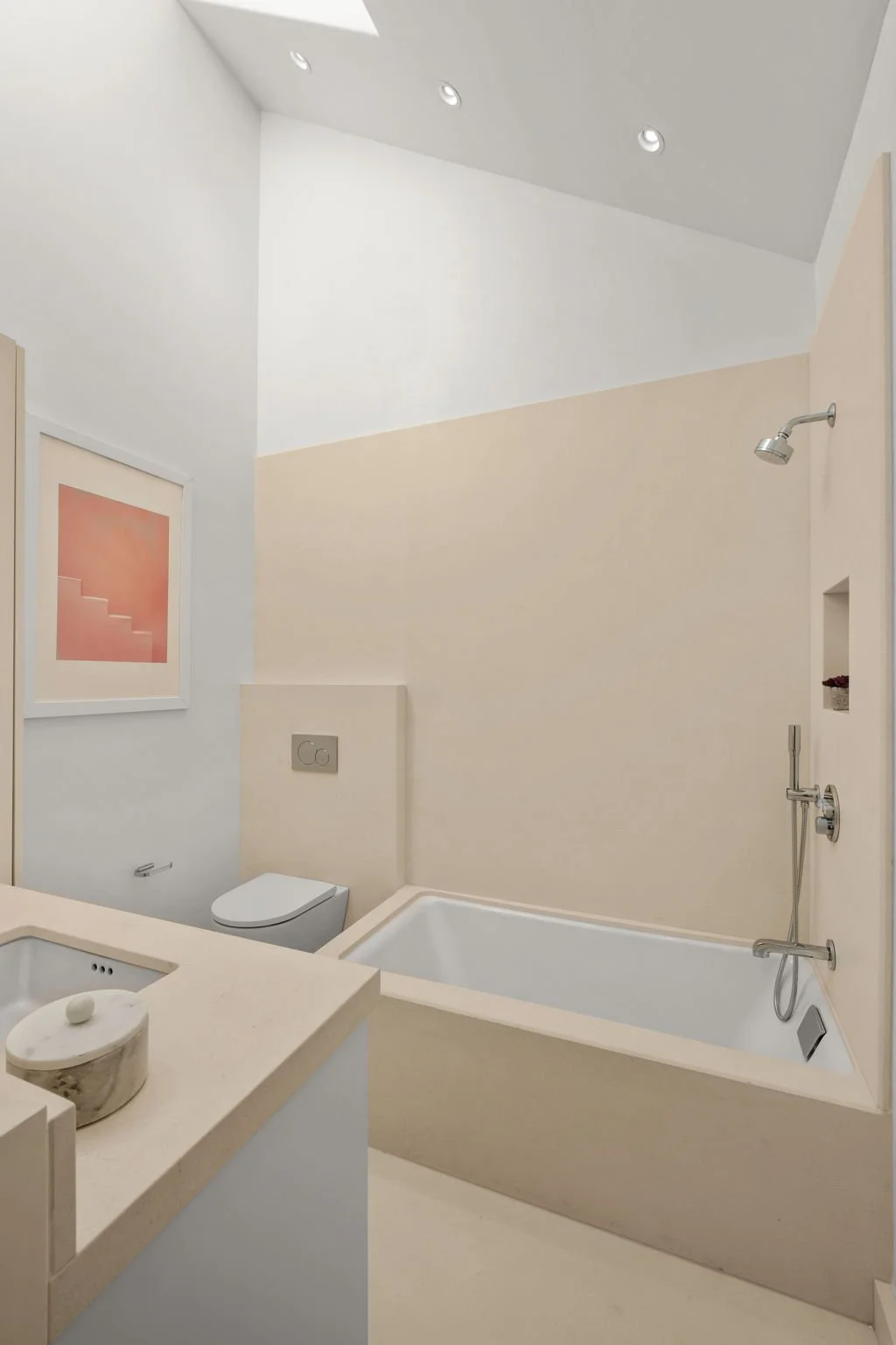 Modern bathroom with a bathtub, toilet, and sink, featuring minimalist design and light-colored walls.