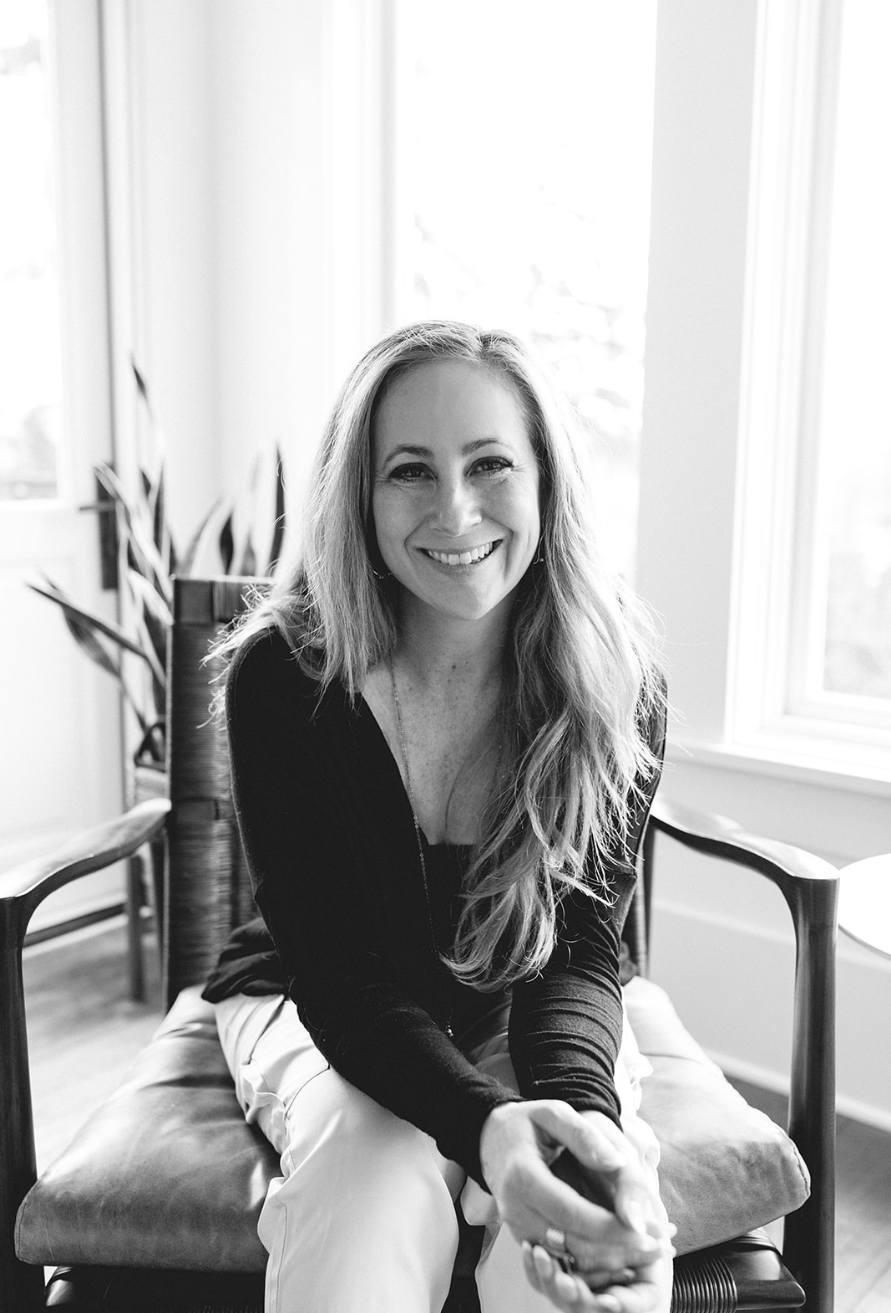 Tara Townsend Seattle real estate broker smiling in black and white portrait, sitting by window with natural light