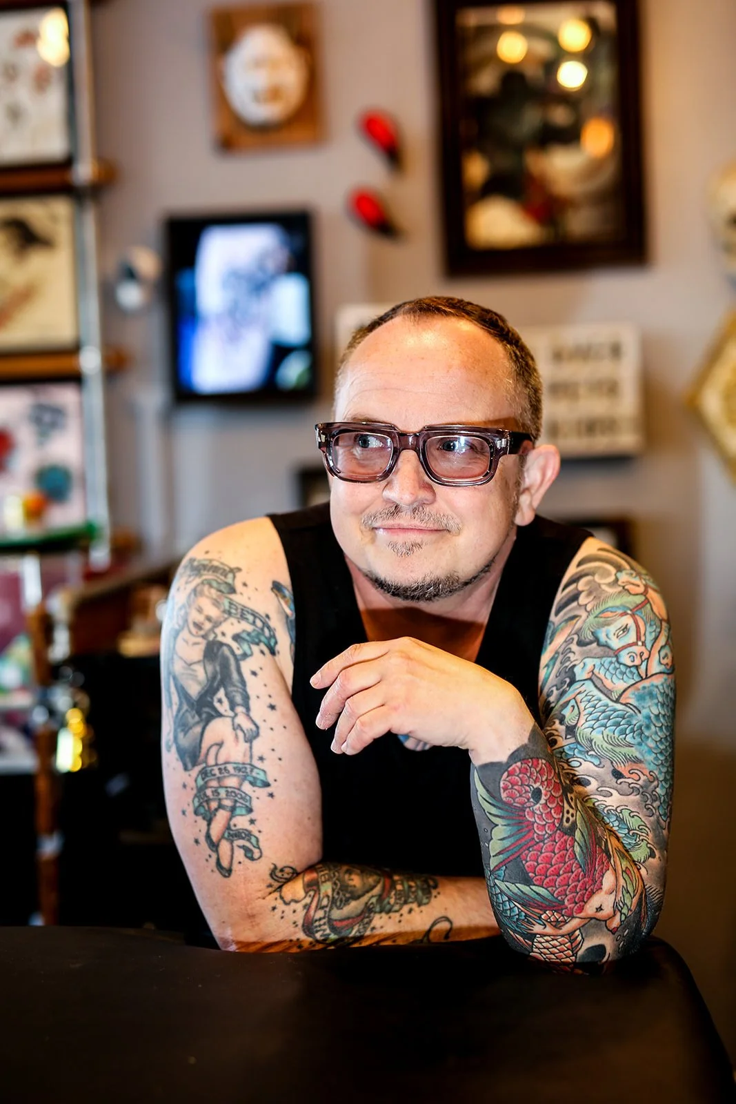 Nik Goodyear at Rabble Rouser Tattoo, wearing glasses, with tattooed arms