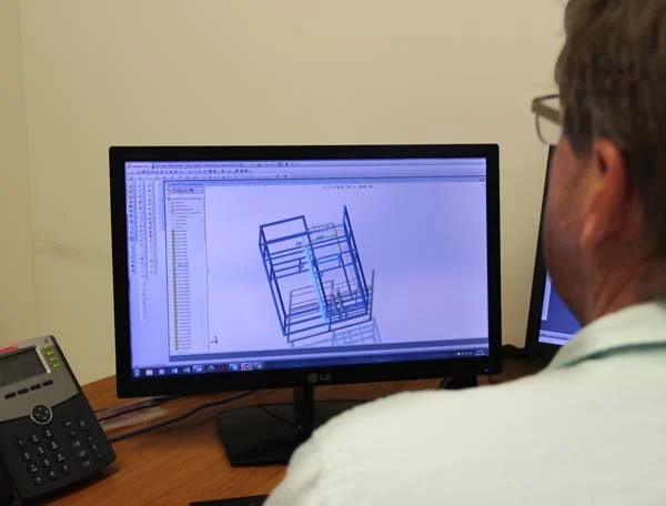 A person working on a computer with a 3D model on the screen.