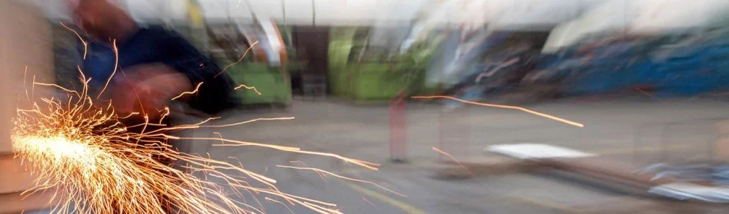 A worker cutting metal with sparks flying in a workshop.