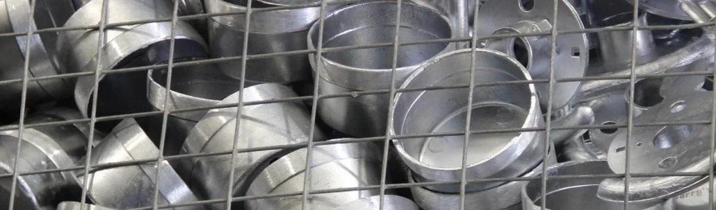Die cast metal pipe fittings stored in a wire grid container.
