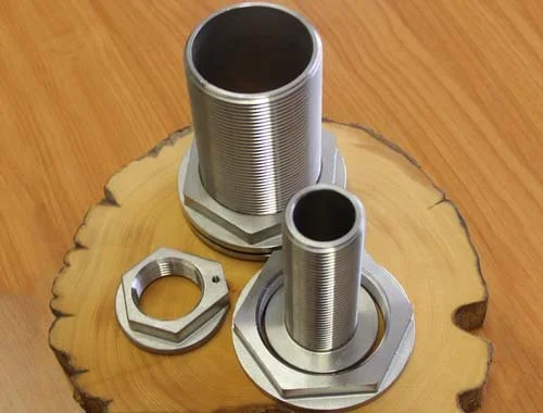 Two large silver metal threaded pipe fittings with hexagonal bases, one smaller and one larger, resting on a wooden surface with a slice of tree trunk as background.