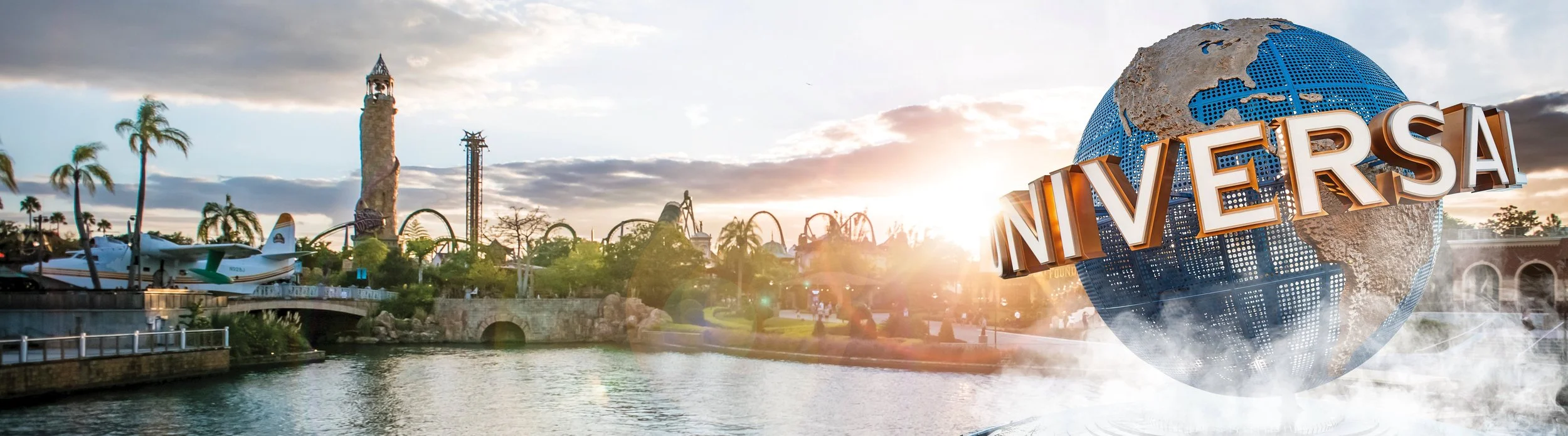 Universal Studios theme park with a roller coaster, a water ride, and the iconic globe with the "Universal" logo, during sunset.