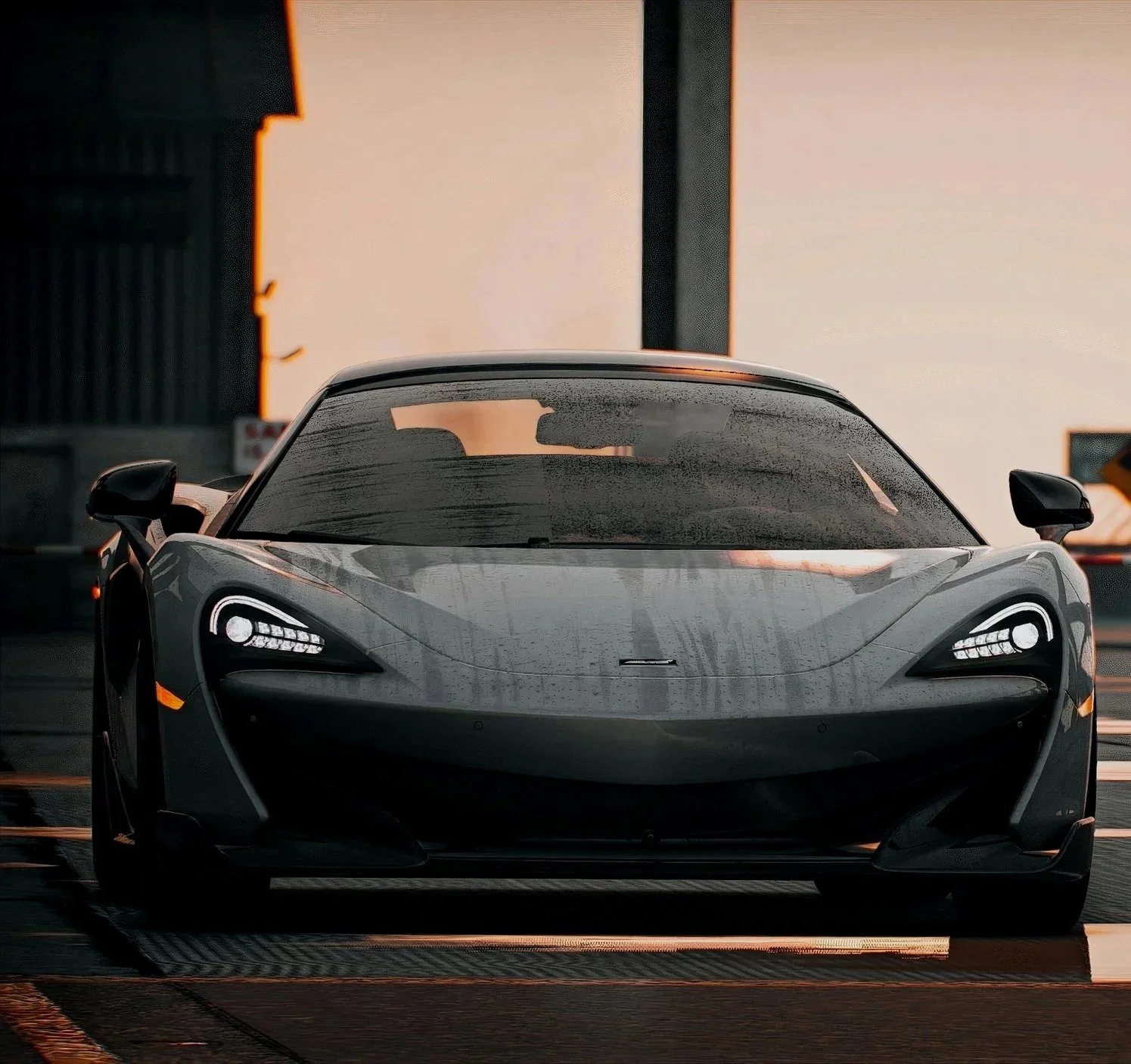 Rear view of a black sports car parked outdoors at sunset, with a modern city skyline in the background.