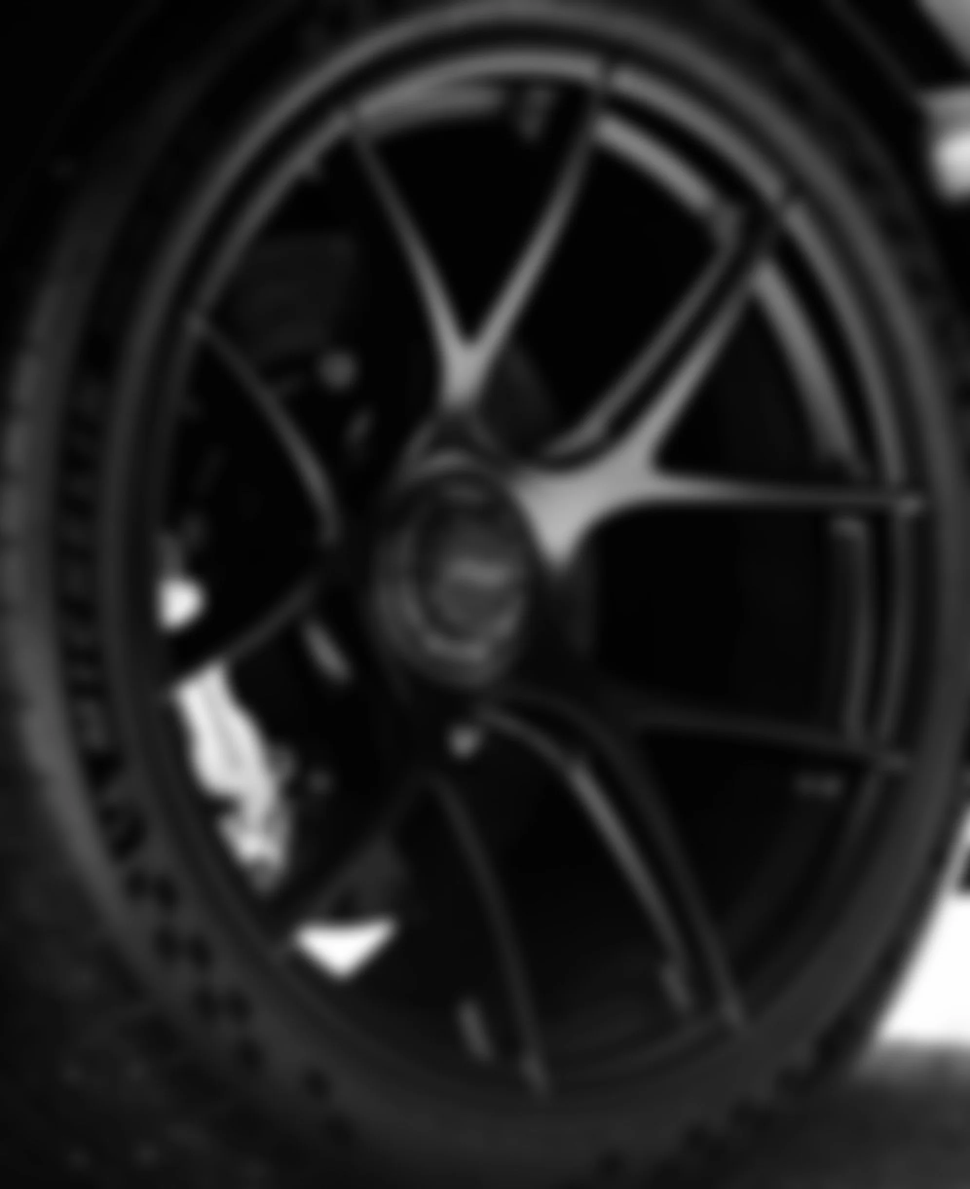 Close-up of a car wheel with a black rim and tire, showing spokes and lug nuts.