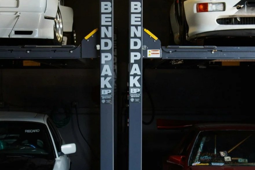 Car lift with two cars parked on the upper level and three cars below, labeled 'BendPak'
