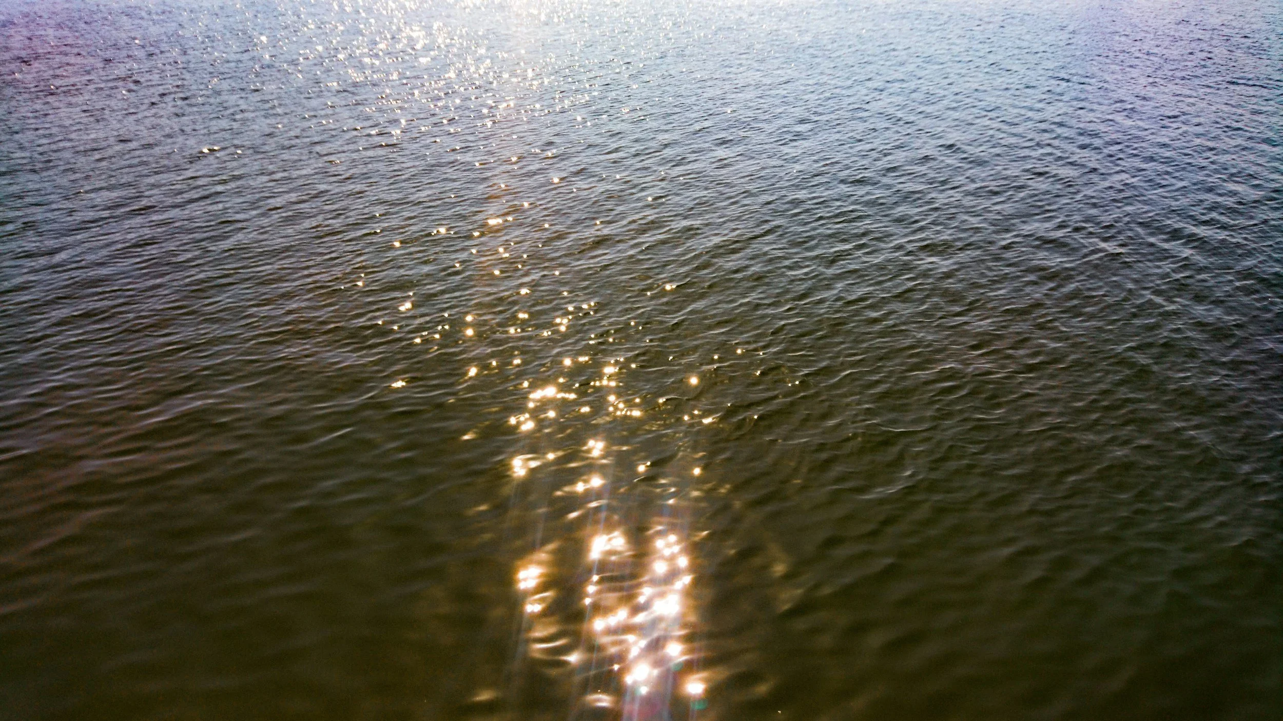 The ocean around sunset, the water glitters with the reflections.