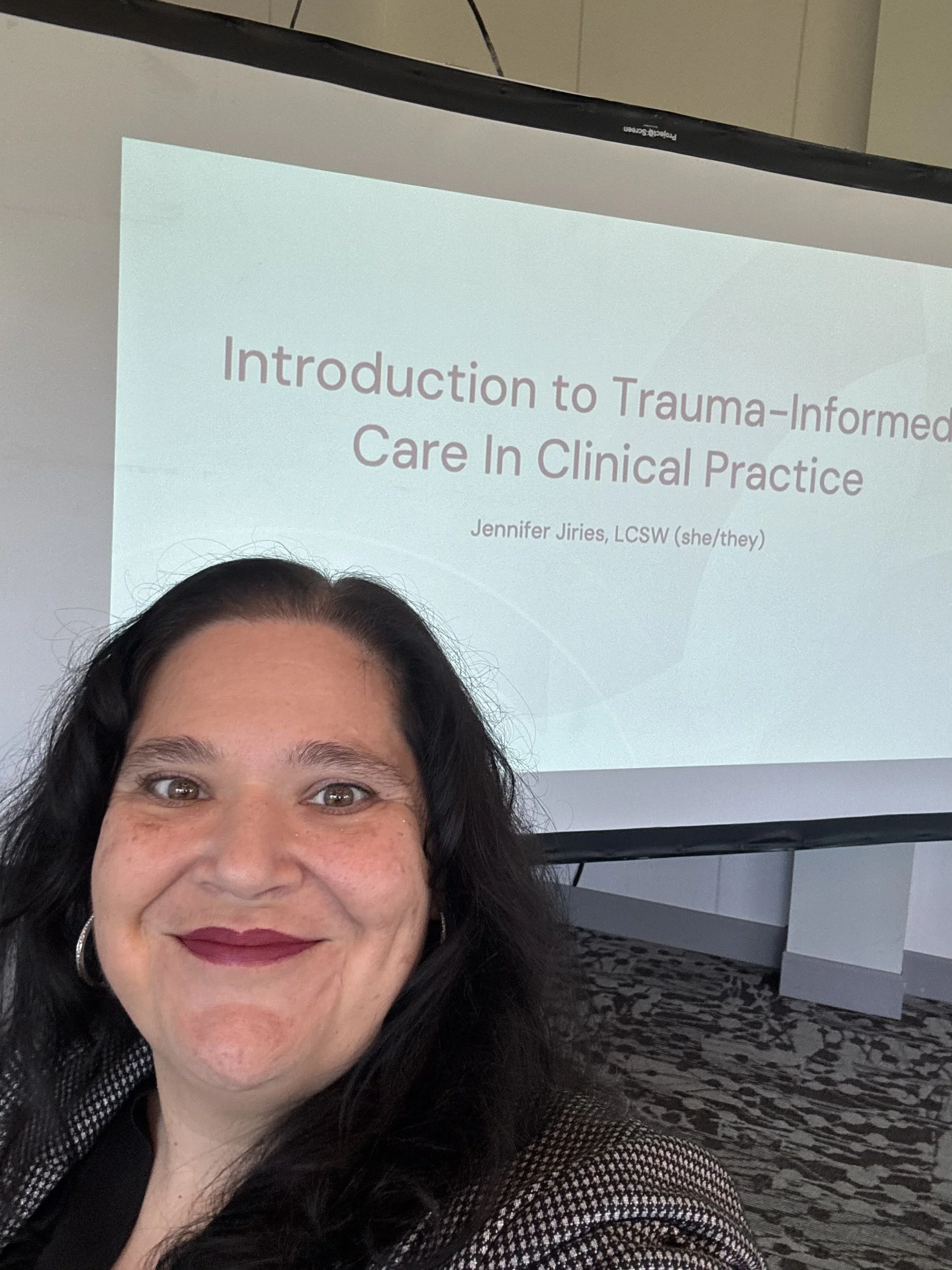 Jennifer in front of a trauma-informed care presentation slide.