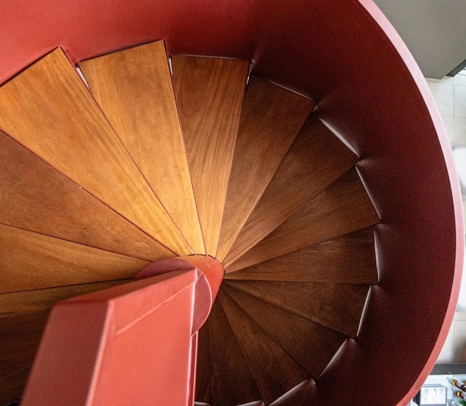 Escada de madeira tubular em forma de espiral vista do topo.