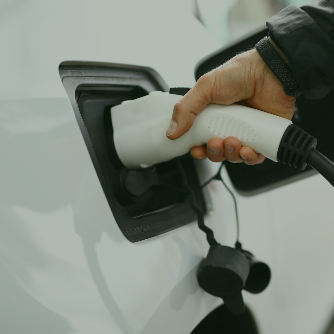 Close-up of a person plugging a charging cable into an electric vehicle's charging port.