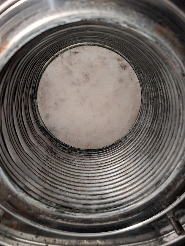 View inside a metal cylindrical pipe or tube showing a clean inner surface with some minor dirt or residue.
