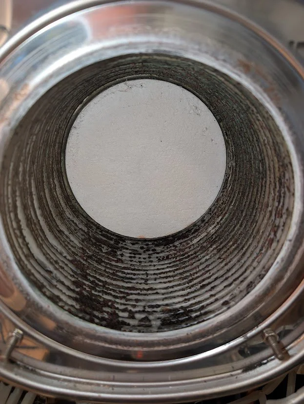 Inside view of a stainless steel beer tap nozzle with residual coffee or beverage stains.