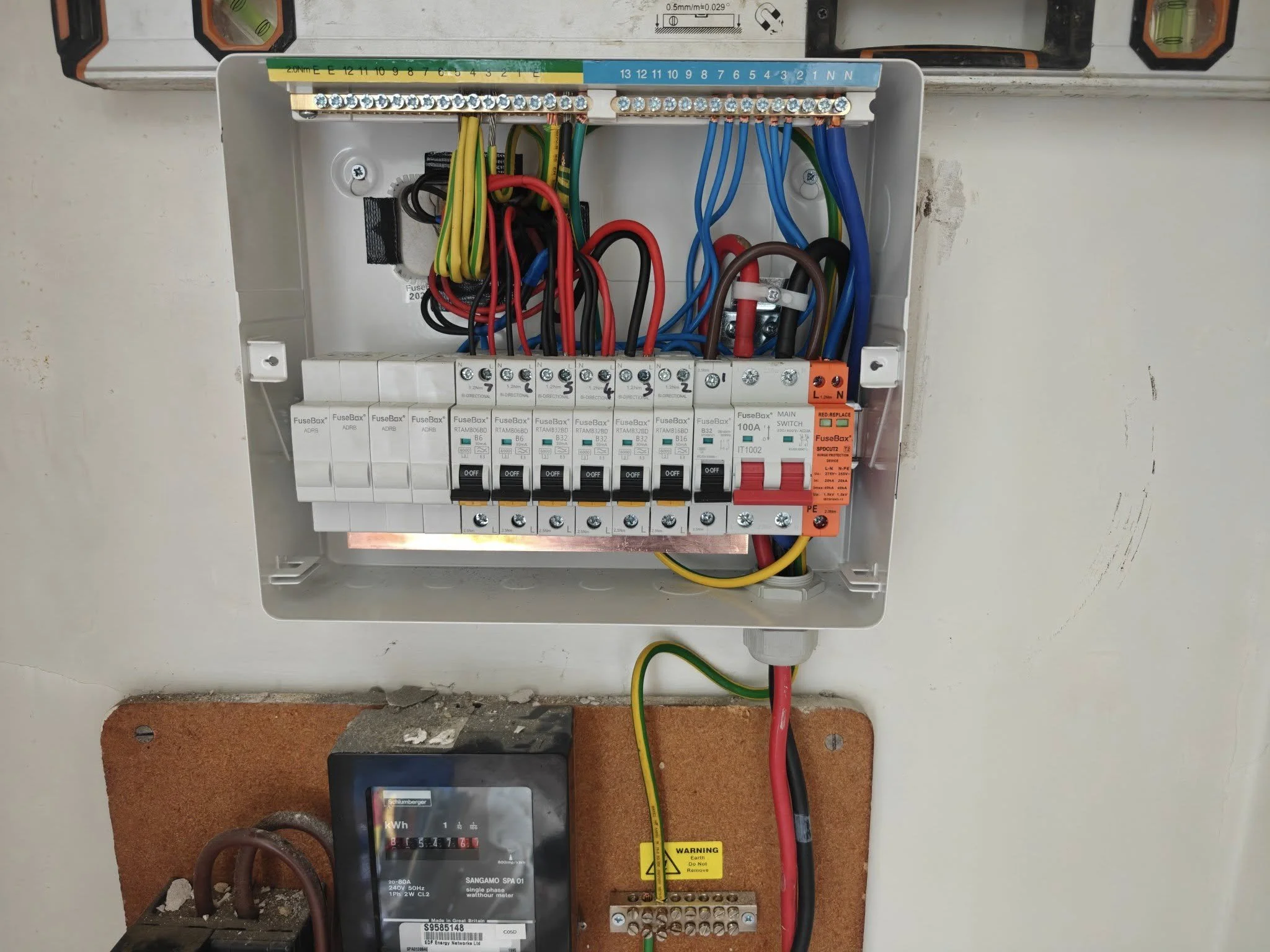 Electrical panel with circuit breakers and wiring, and an electric meter below.