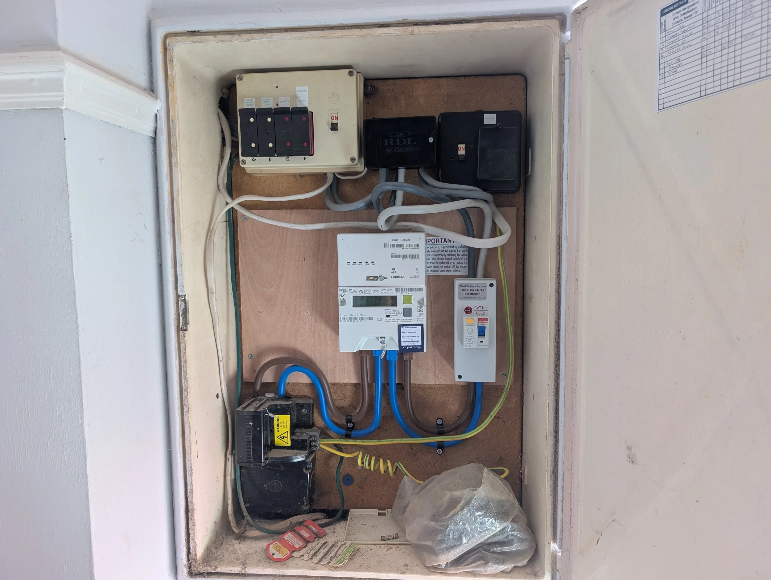 Electrical breaker box with switches, wires, and a control unit mounted inside an open wall panel.