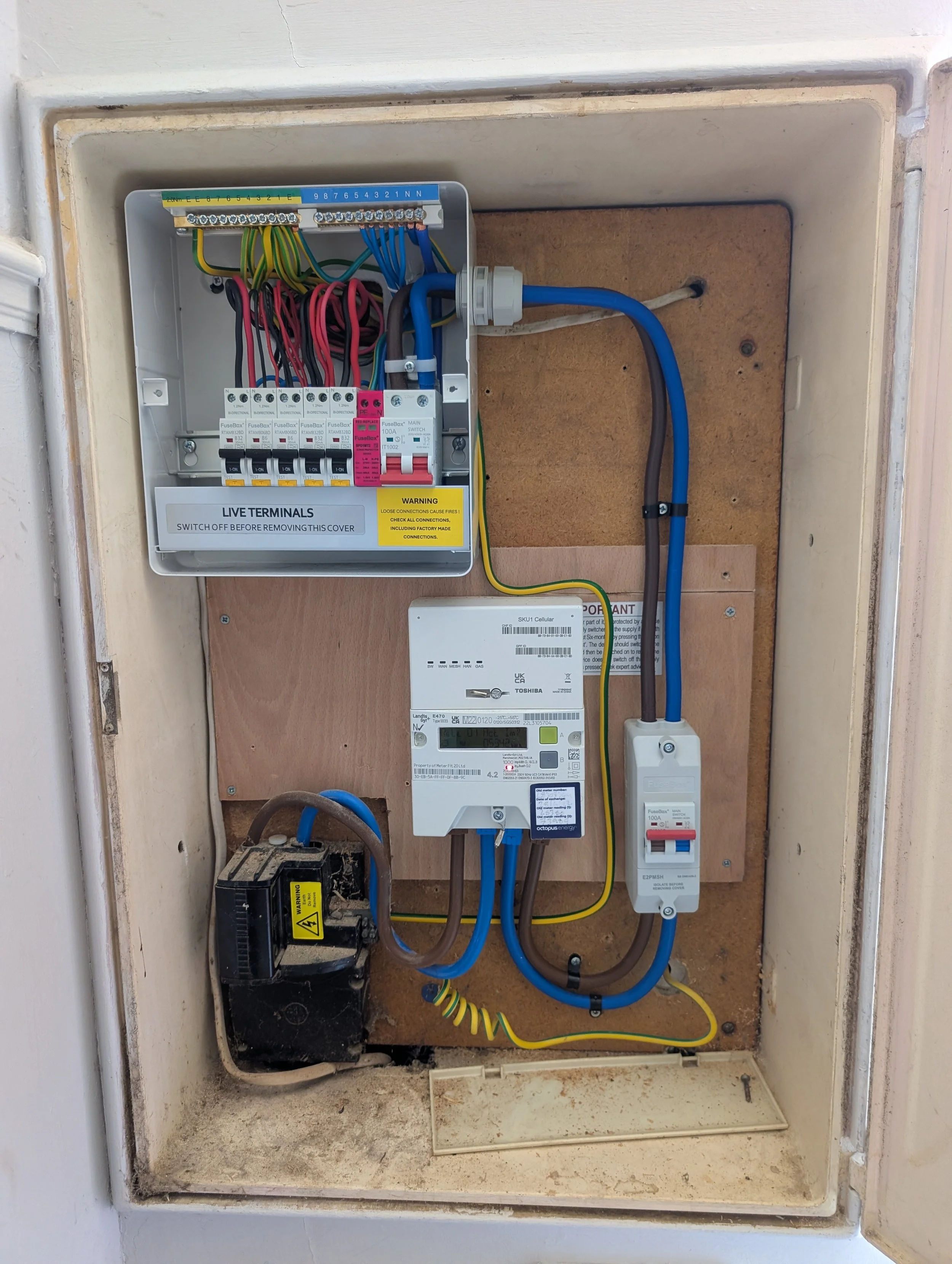 An electrical box with various wires, circuit breakers, and a digital meter inside a wall enclosure.