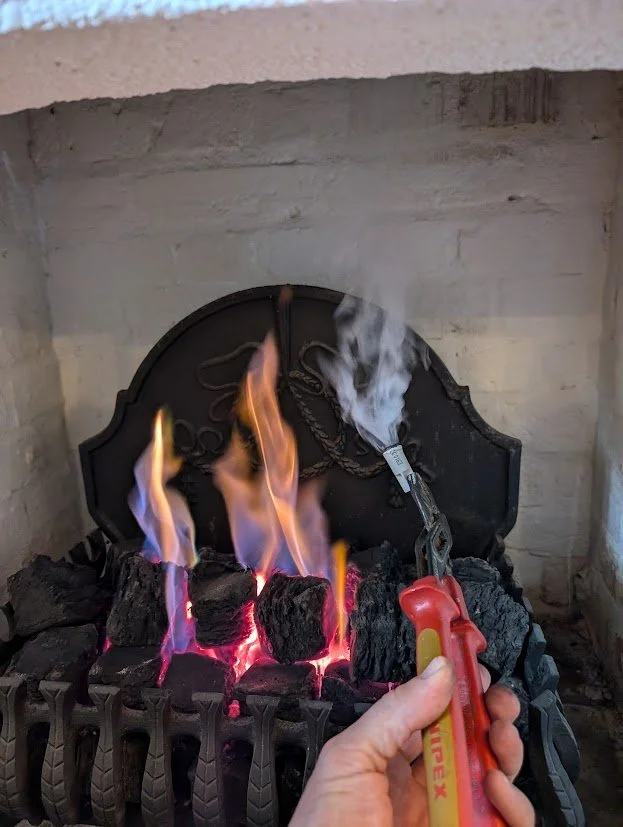 Person is lighting bricks on a fireplace with a safety lighter, and the bricks are on fire with visible flames and smoke.