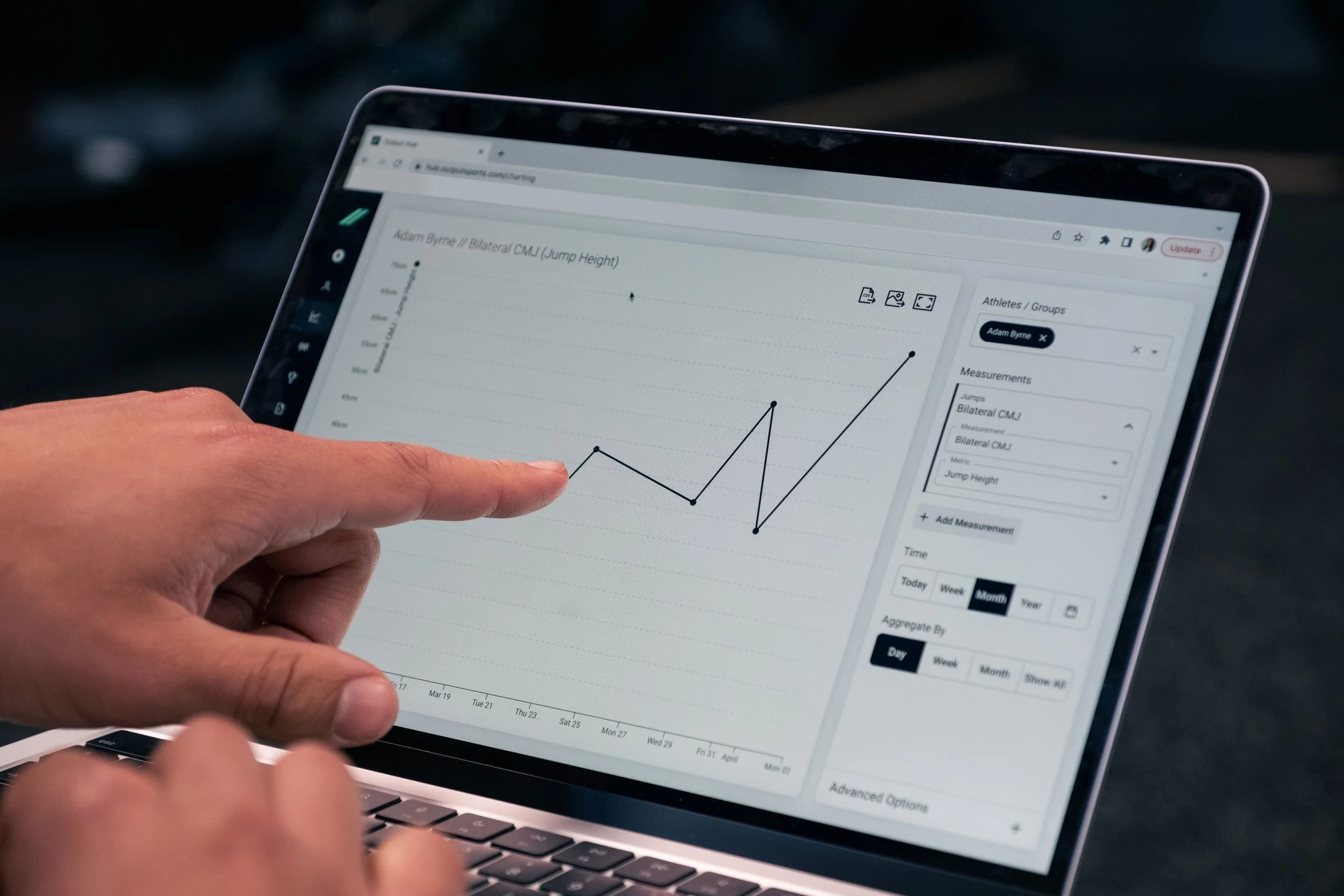 Person pointing at a line graph on a laptop screen displaying jump height measurements over time.