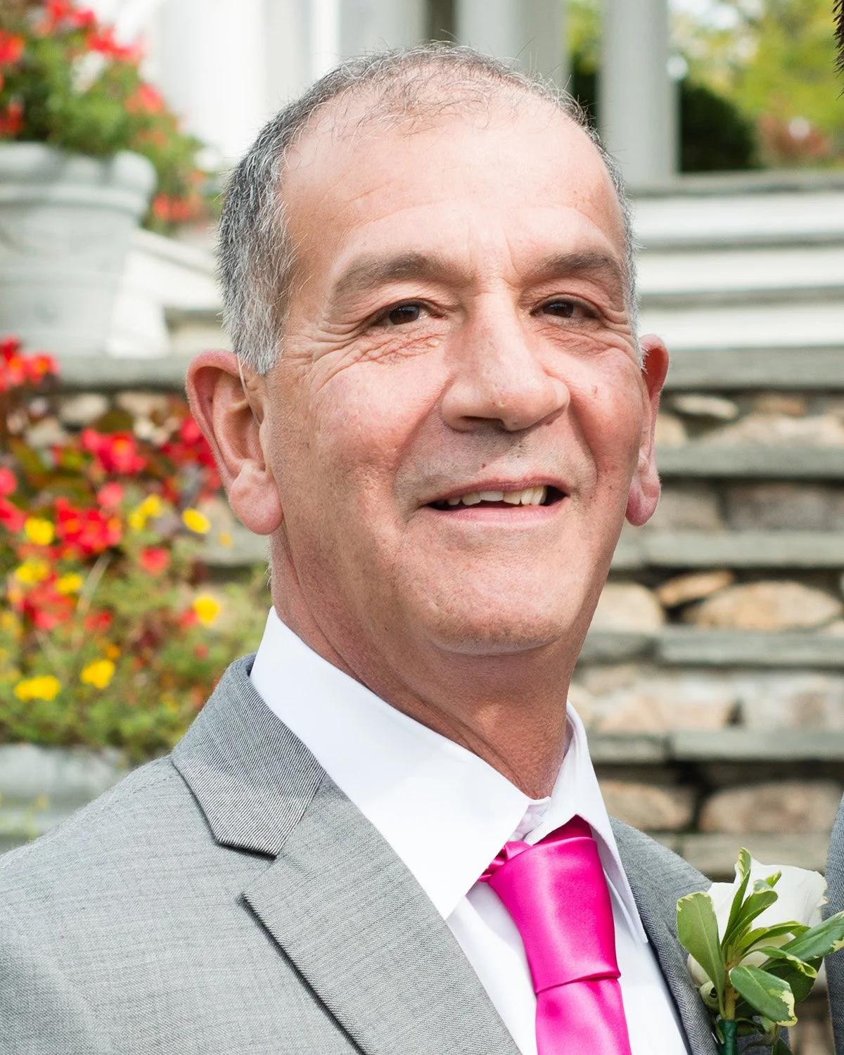 Joseph P. Niccoli Sr. smiling outdoors, wearing a suit jacket and pink tie