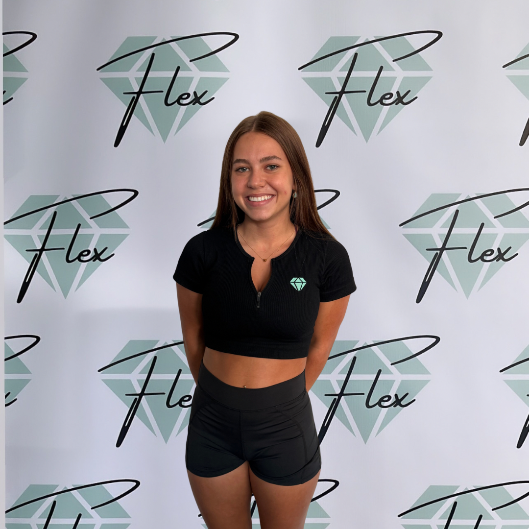 A young woman with long brown hair, wearing a black crop top with a diamond logo, black shorts, and earrings, standing in front of a white background with the 'Flex' logo and diamond graphic.
