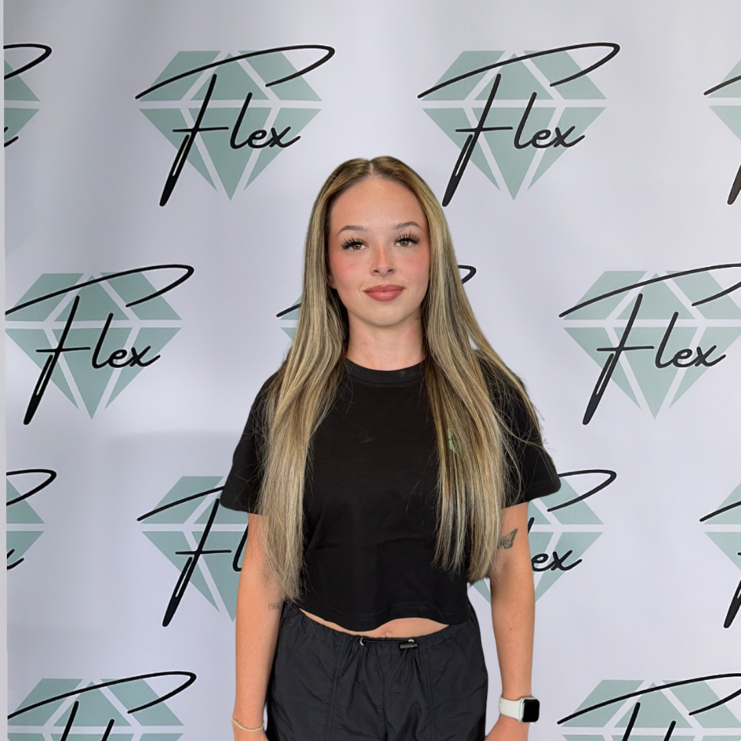 Young woman with long blonde hair standing in front of a backdrop with a diamond logo and the word "Flex" repeated multiple times.