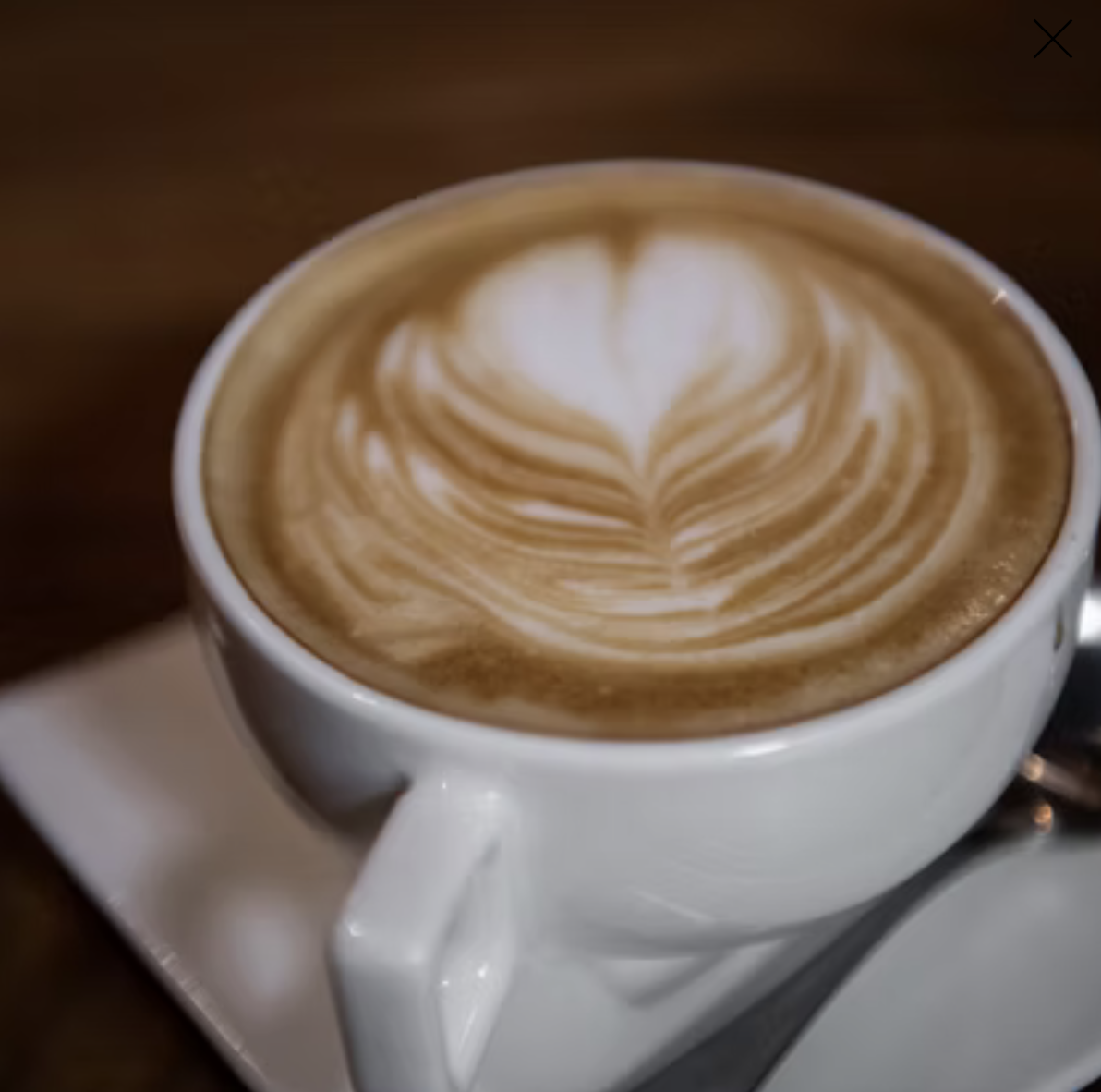 A cup of coffee with latte art in a white mug on a saucer.