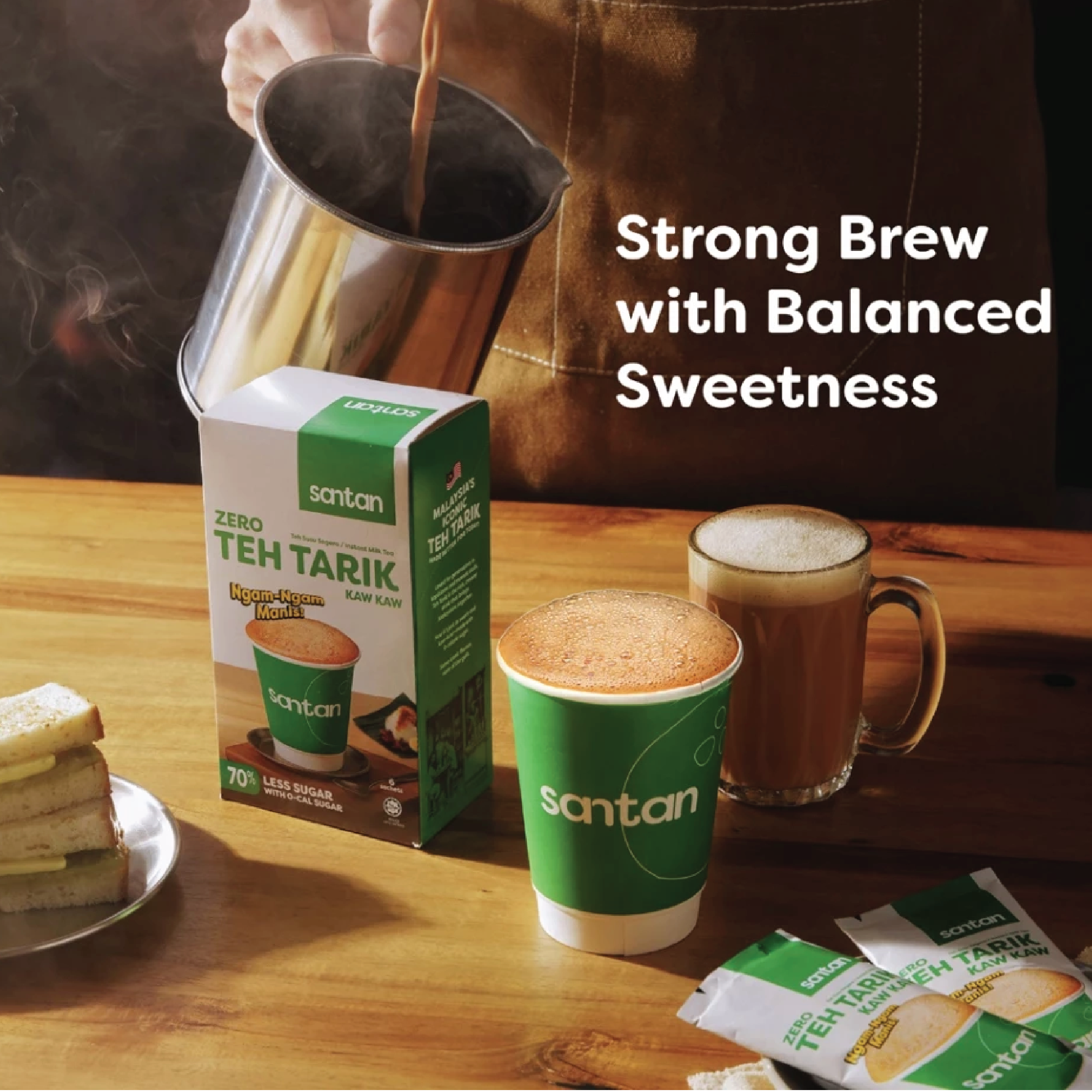 A glass of tea, a cup of frothy tea, and a mug of tea placed on a wooden table, with a carton and packets of Santan Zero Teh Tarik tea. A person is pouring hot beverage from a metallic pitcher. The text reads 'Strong Brew with Balanced Sweetness'.