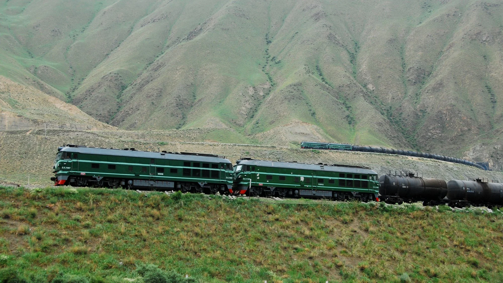  合成圖：雙機東風 4 型內燃機車牽引油罐車行駛在下新光展線，近處為下層展線，遠處為下新光車站所在的上層展線，這個展線擁有一個螺旋形隧道。攝於2010年 