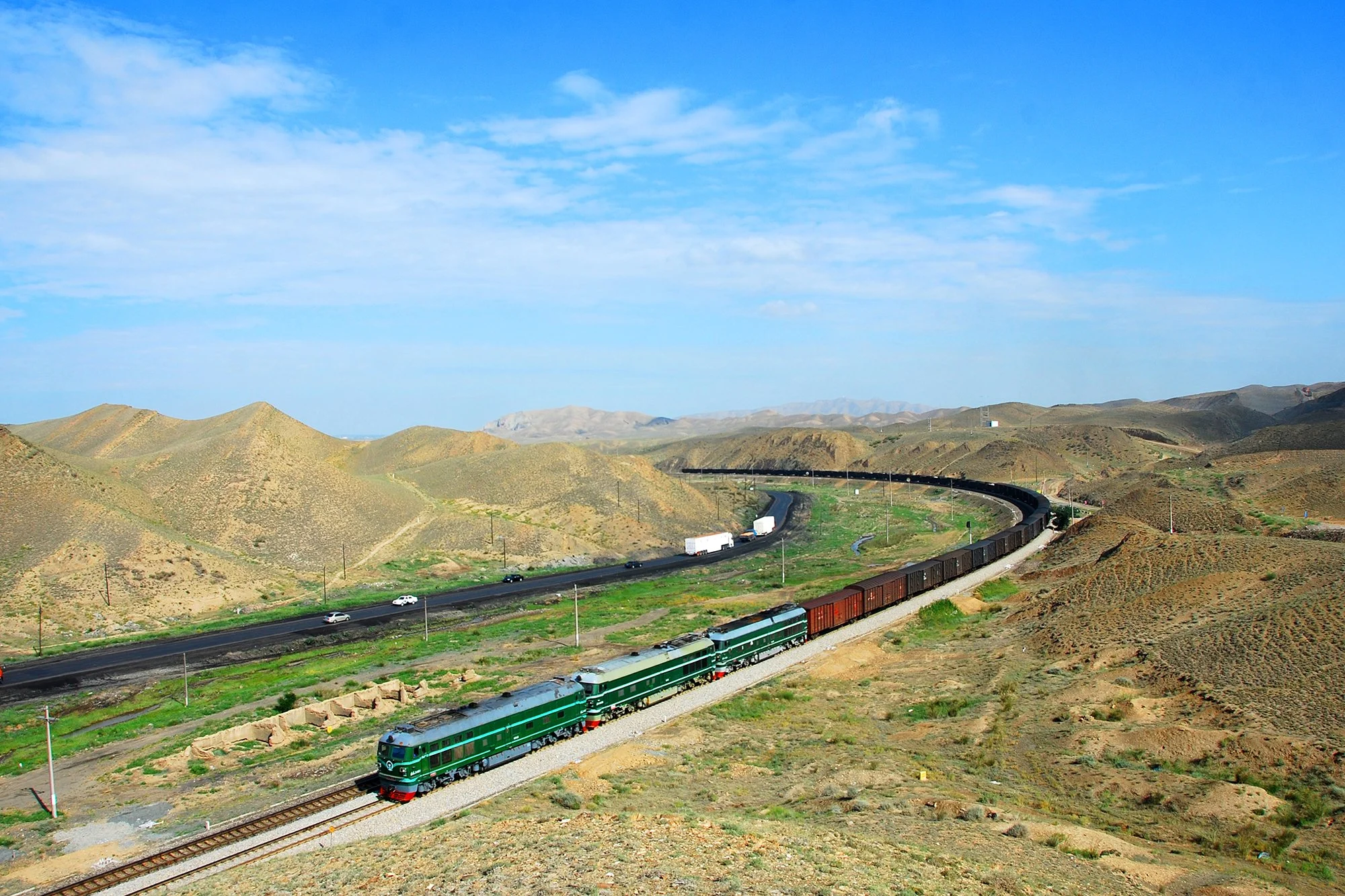  蘭新鐵路在烏拉泊以北進入一段長約 5 公里的山谷，鐵路在此蜿蜒曲折，共設有 8 條曲線。圖中的三機貨列正在通過第四 處曲線。這段路線已經在 2020— 2021 年被裁彎取直。攝於2010年7月。 