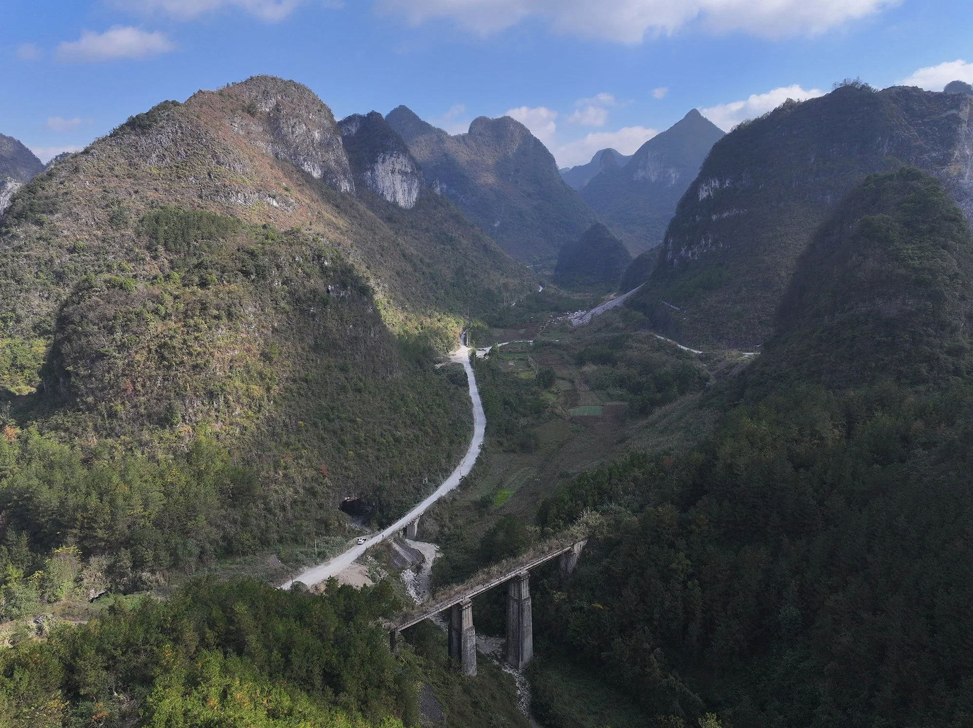  黔桂鐵路回龍道是一處展線，它為了降低線路坡度，因而只能增加線路長度，在喀斯特地貌的山區盤旋一圈。回龍道位於金城江到貴定之間的南丹附近，這段路線穿越山區，最小曲線半徑只有173米，最大坡度高達29‰，列車跑起來非常慢，速度大概只有21到60公里每小時。而2009年以後的提速線路將曲線拉直了不少，最小曲線半徑提升到1600米，最大坡度也降到13‰，列車速度可以達到120到160公里每小時，其中柳州到金城江這一段甚至可以飆到200公里每小時。攝於2021年3月。 