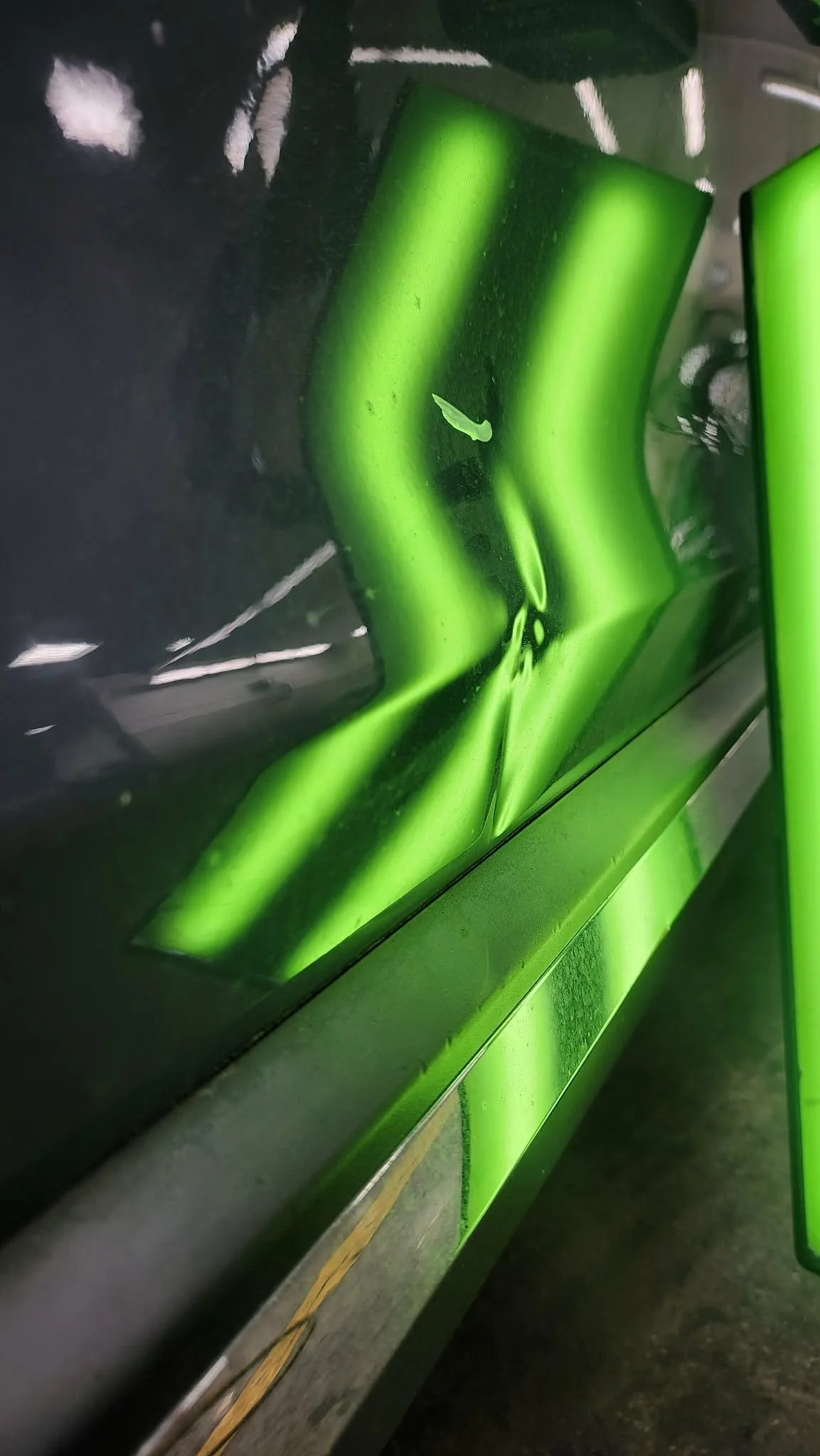 A green and black bicycle with a damaged green frame, showings dents and scratches.