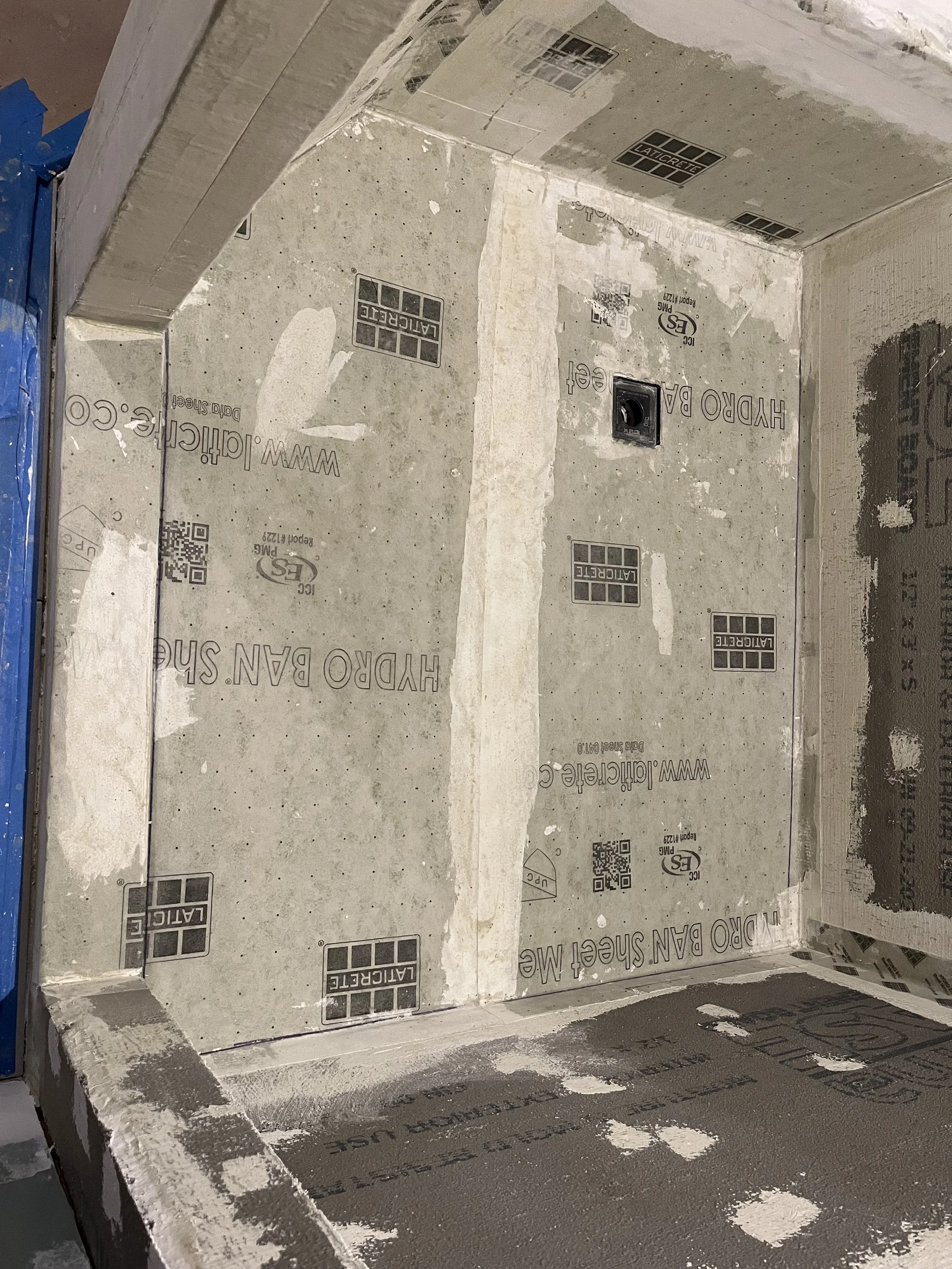 Construction of a shower area with drywall installed and waterproofing membrane on the walls.