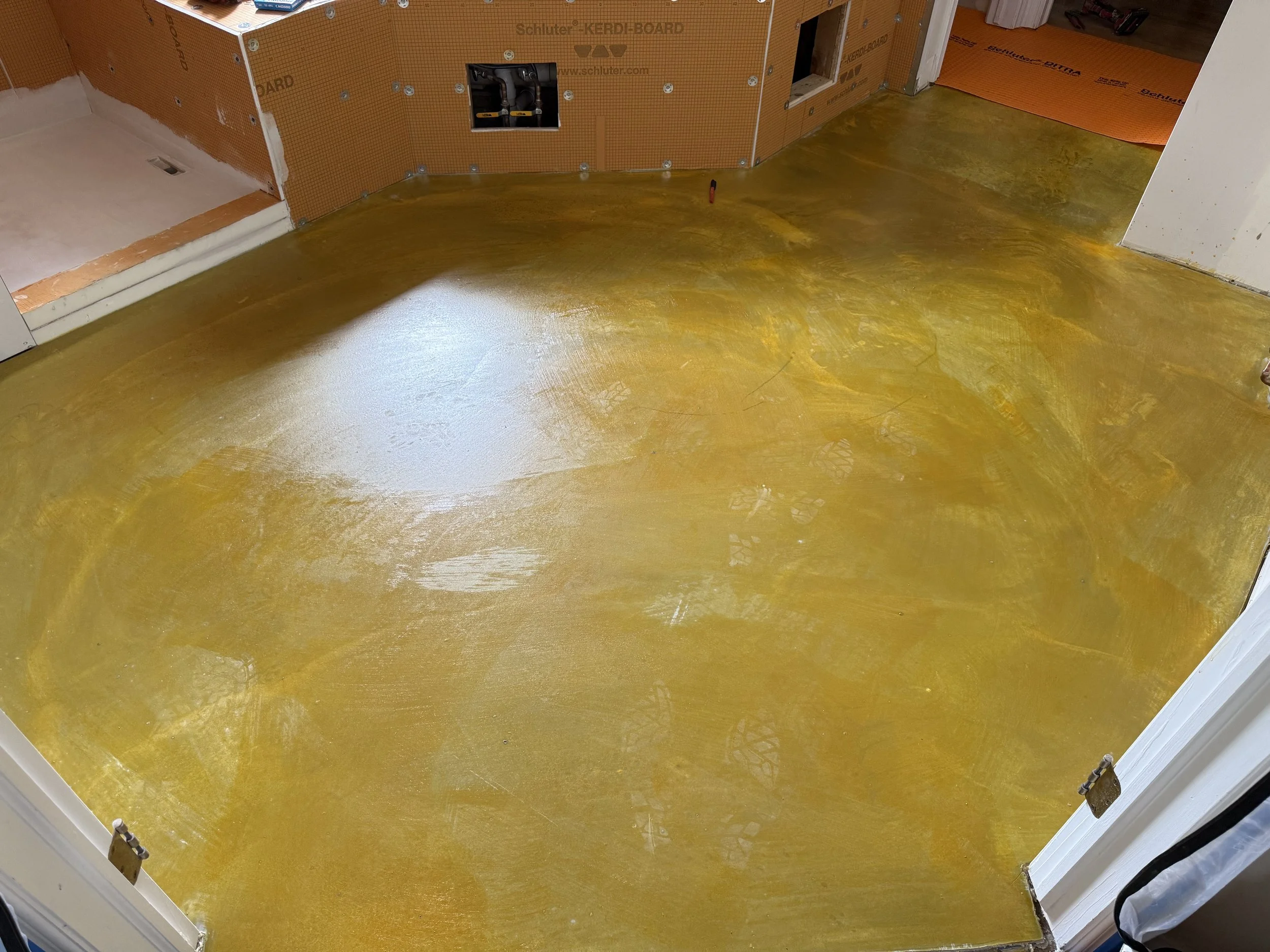 Freshly applied yellow epoxy coating on a hardwood floor in a room under construction.