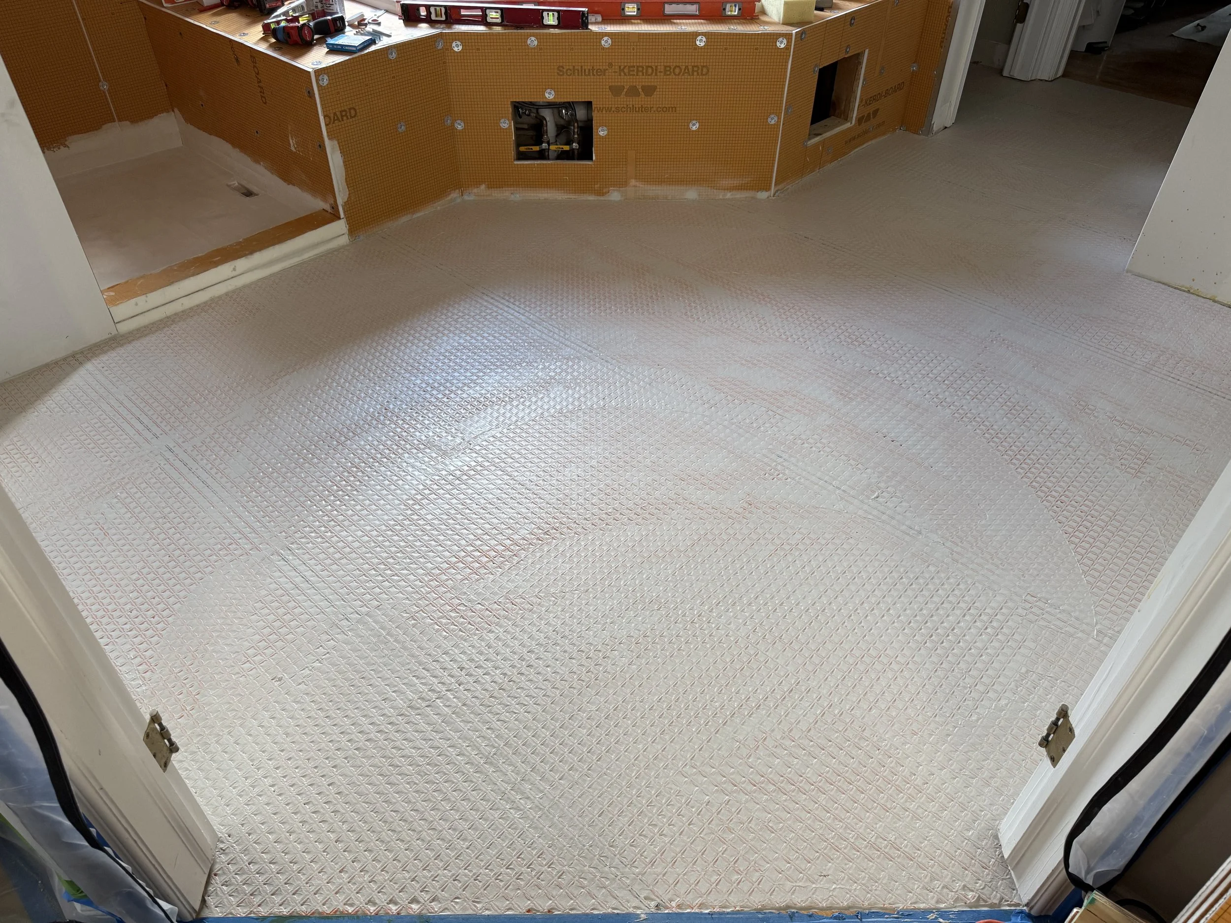 Room under construction with a metallic flooring, partially finished walls, and a space for unseen fixtures or appliances.
