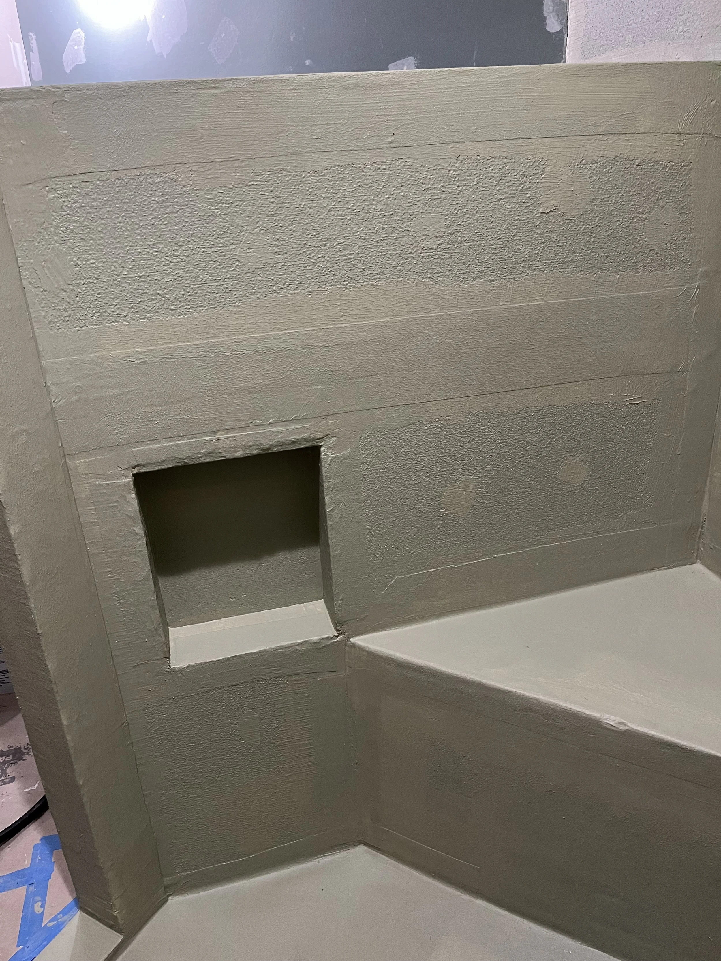 Close-up of a painted wall corner with a square cutout and textured wall surface.