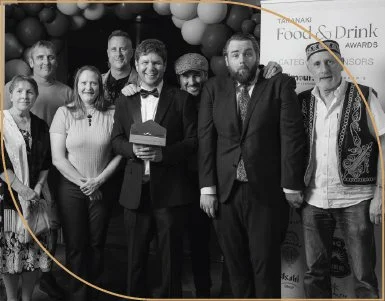 Group of people at an awards event, with one person holding a cake, smiling for the camera.