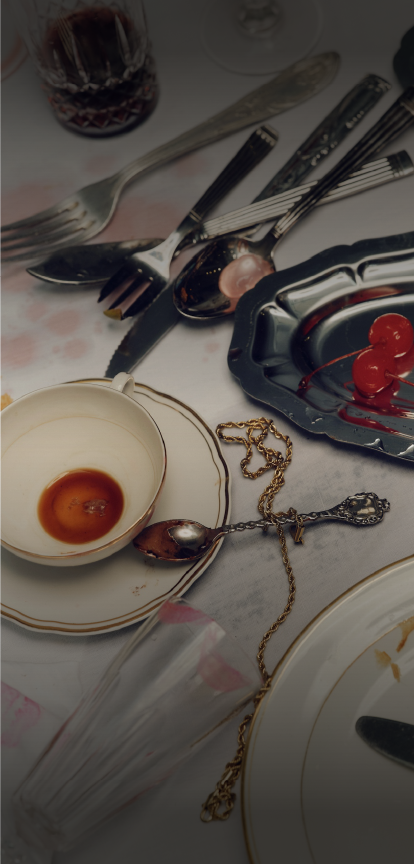 A table with used utensils, a cup with leftover sauce, a chain, a small spoon, and a tray of cherries.